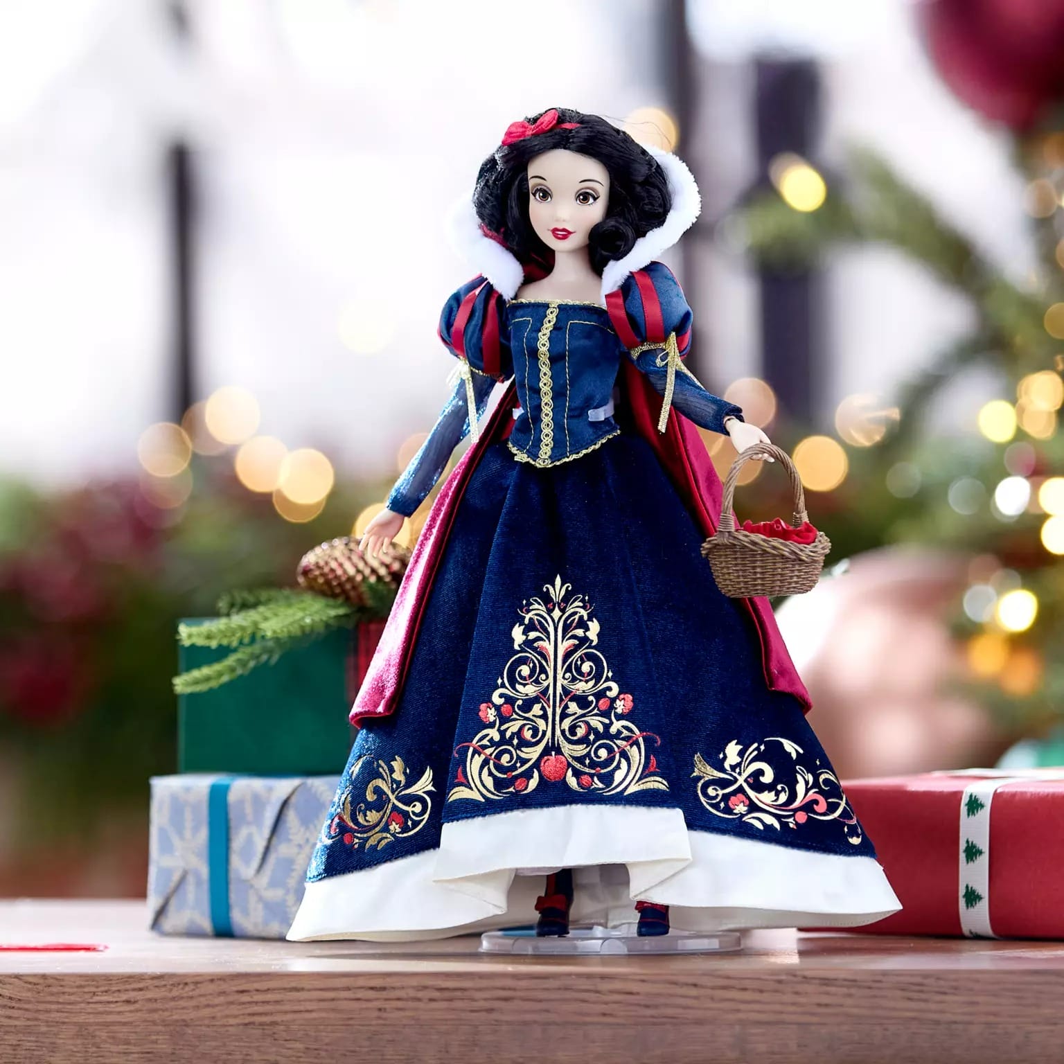 A Disney Store Snow White doll in a blue and red dress stands by 2025 Disney Christmas Merchandise, holding a basket.