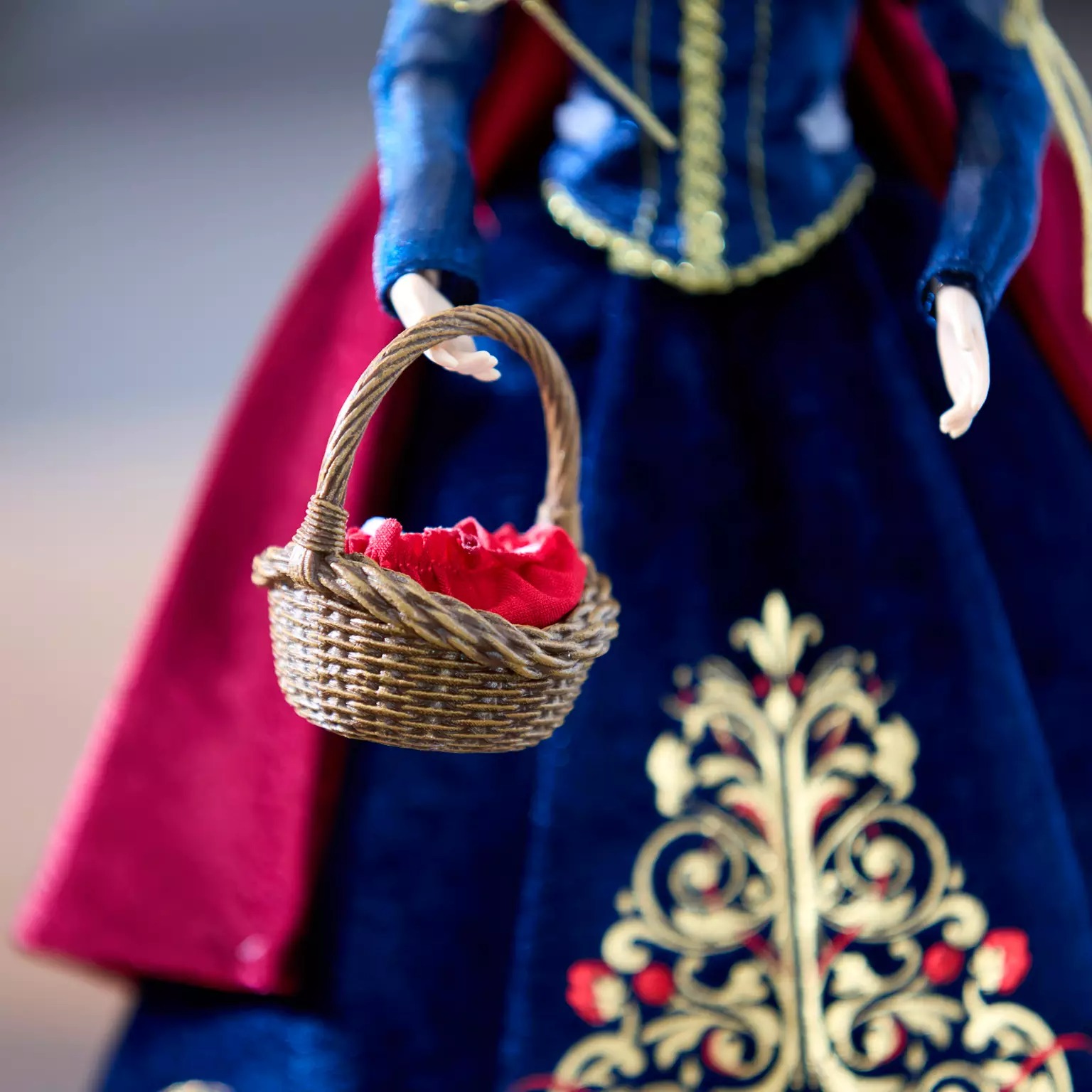A Disney Store doll in a blue and red dress holds a small basket—perfect for 2025 Disney Christmas merchandise.