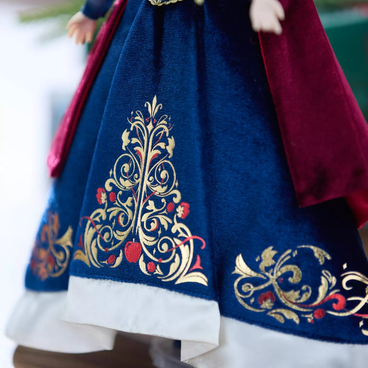 A blue and white dress with gold and red floral designs, part of the 2025 Disney Store Christmas merchandise for dolls.