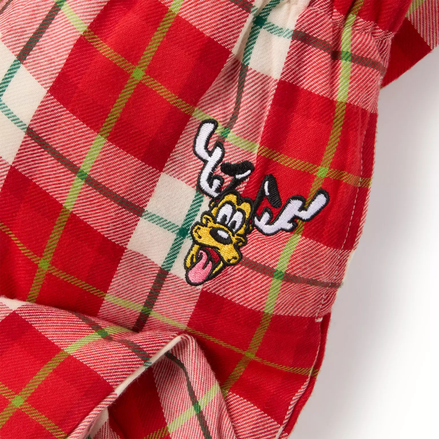 Red plaid fabric featuring an embroidered cartoon dog with antlers, part of Disney Christmas merchandise.