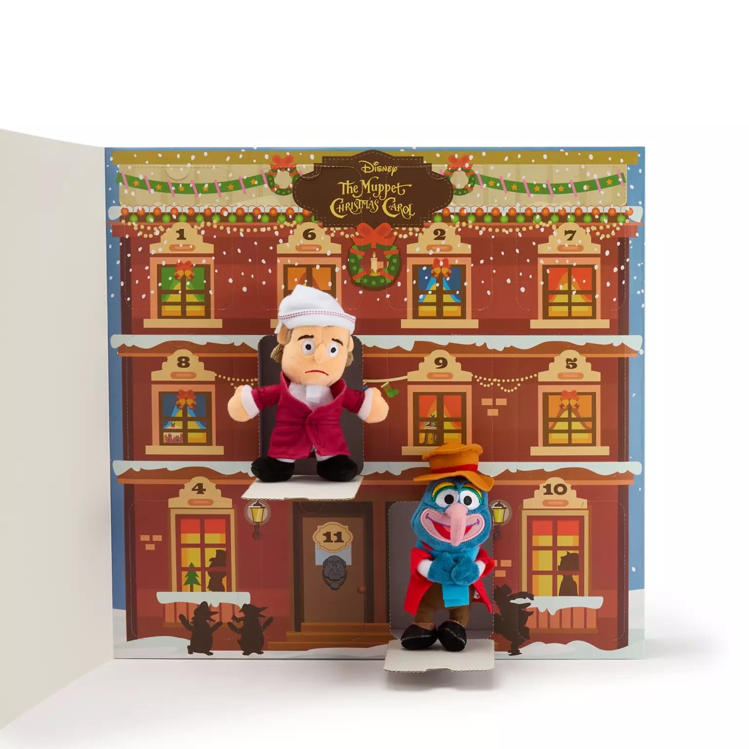 Two Muppets plush toys sit before a Christmas calendar styled like a festive Muppet Christmas Carol building.