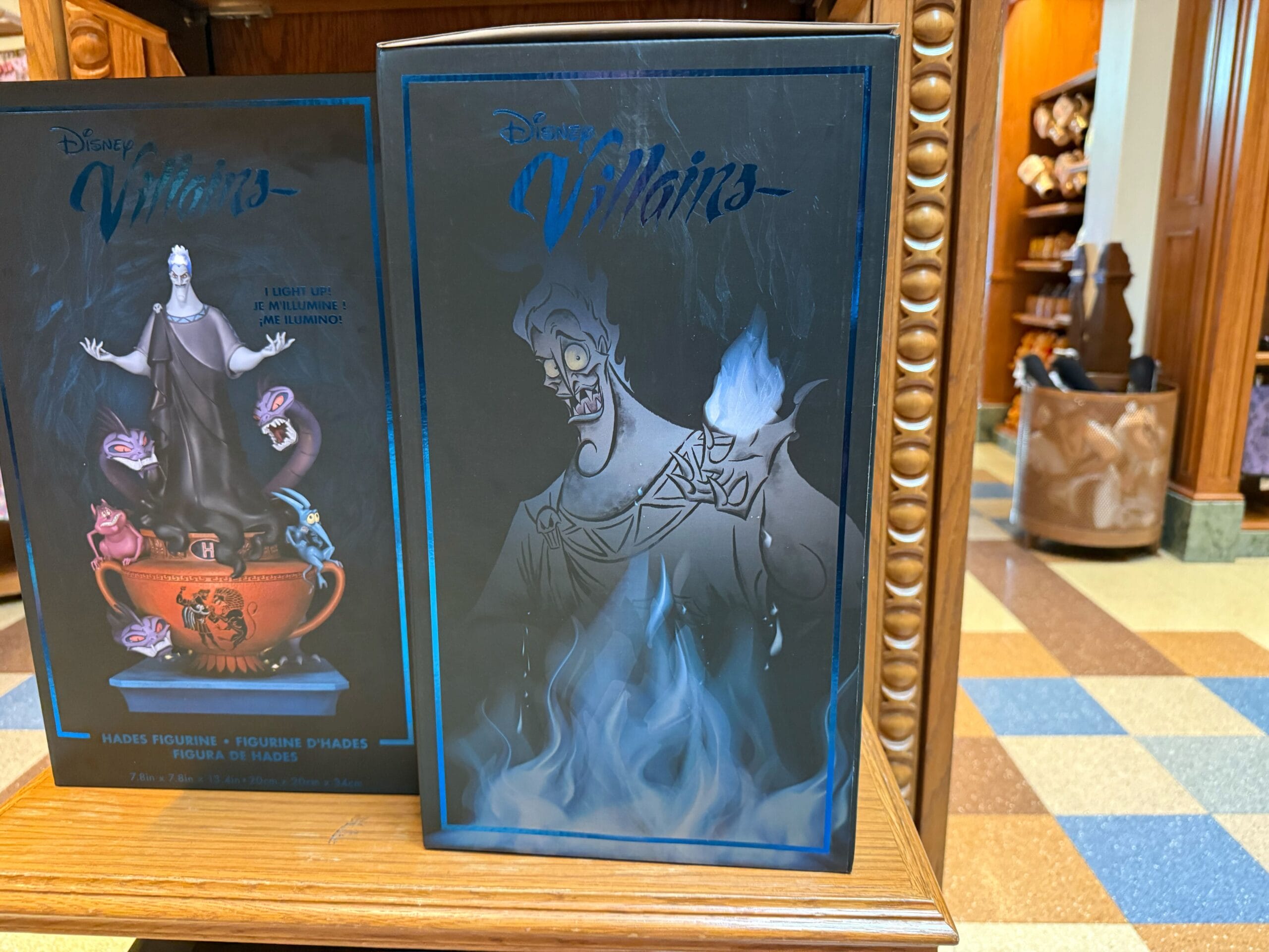 A Disney Villains Hades figure box is on display in a store at California Adventure with tiled floor and wooden shelves.