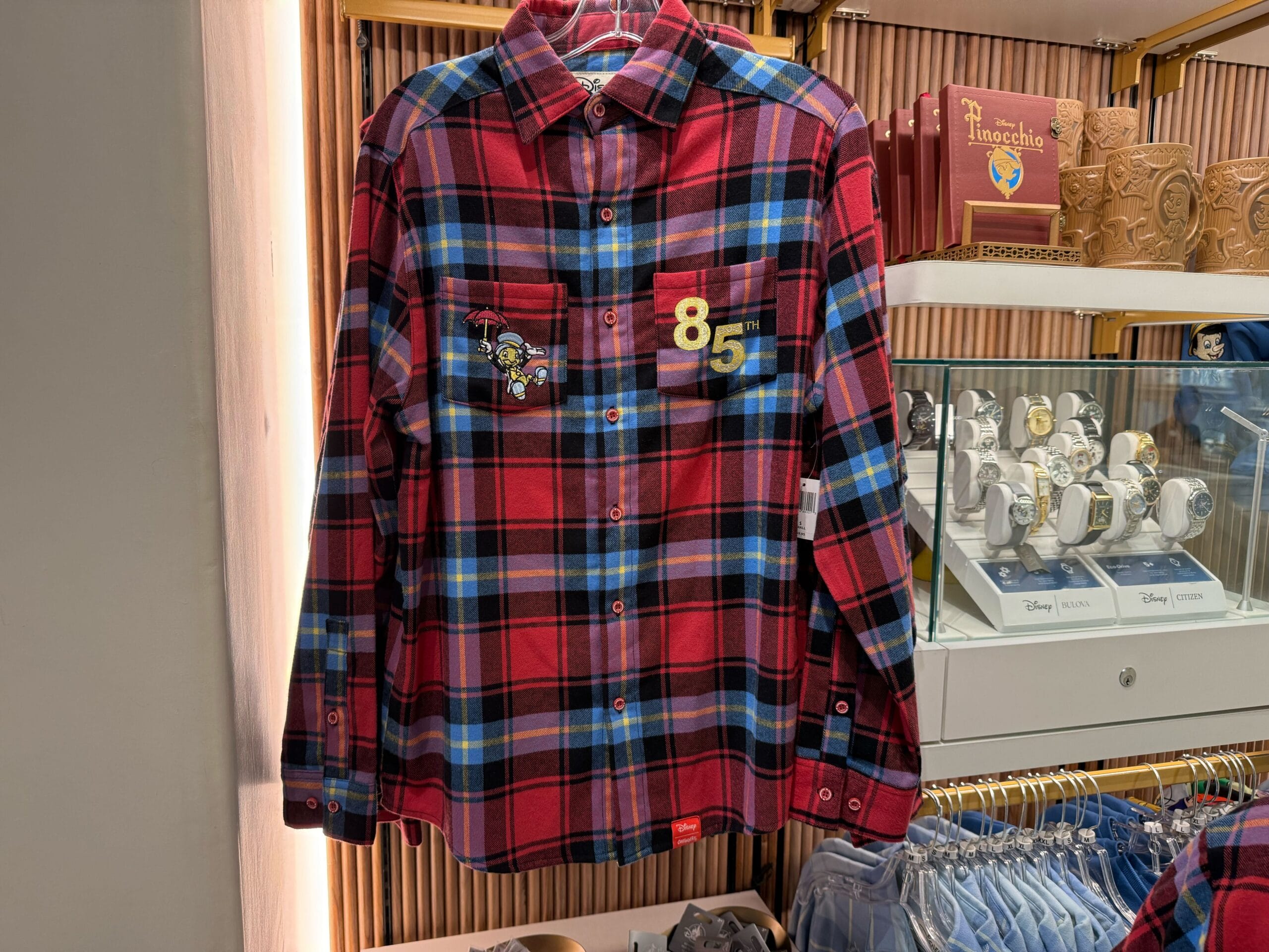 A red and blue plaid shirt with Pinocchio-themed patches hangs on display for Pinocchio’s 85th Anniversary in Disneyland.