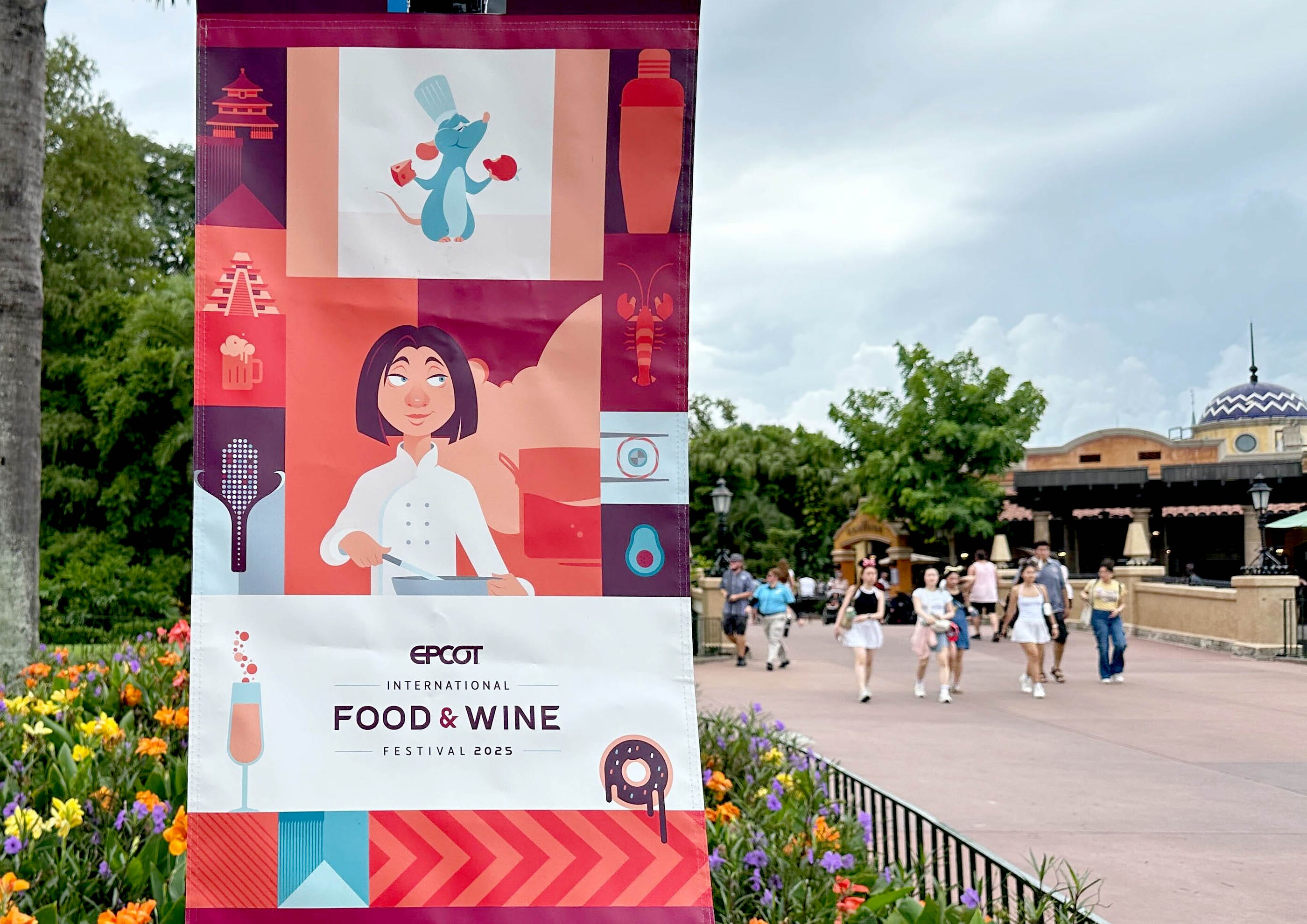 A banner for EPCOT International Food & Wine Festival featuring cartoon chefs and food icons, with people walking in the background.