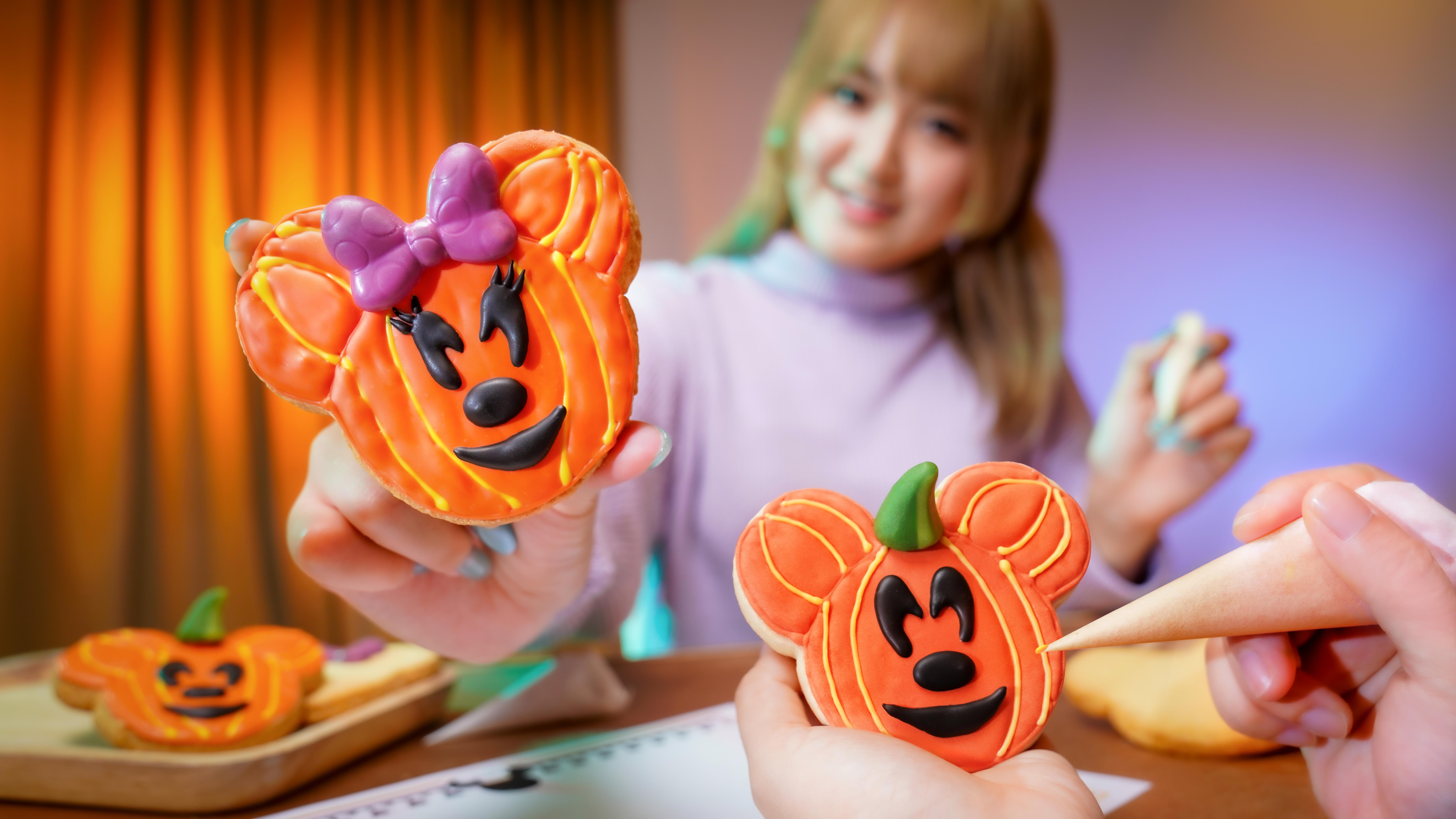 A woman decorates pumpkin-shaped cookies with Disney Villains faces for Hong Kong Disneyland’s 20th Anniversary.