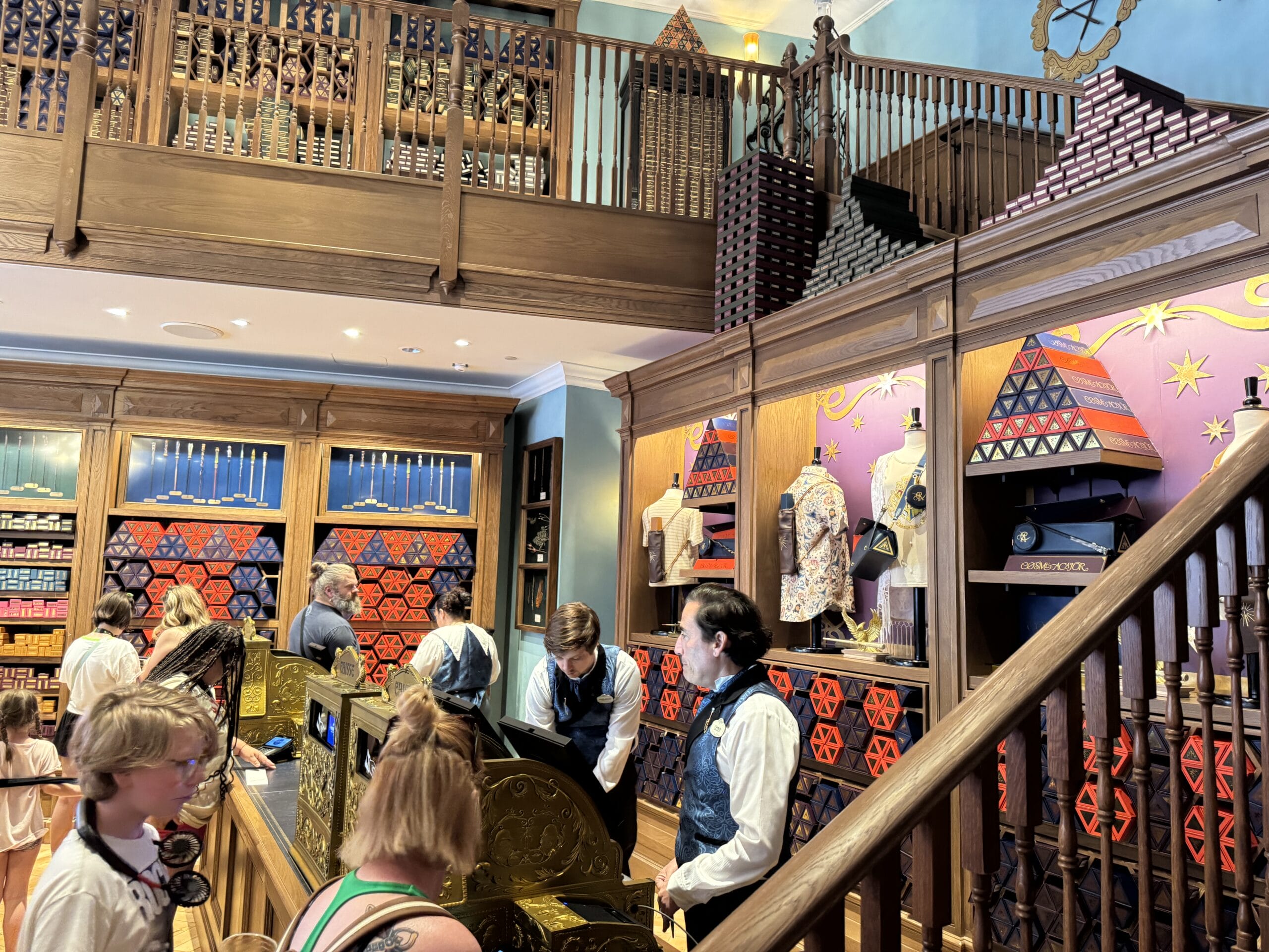 People shop at Cosme Acajor, a themed store with Baguettes Magique, colorful displays, and staff in vests behind the counter.