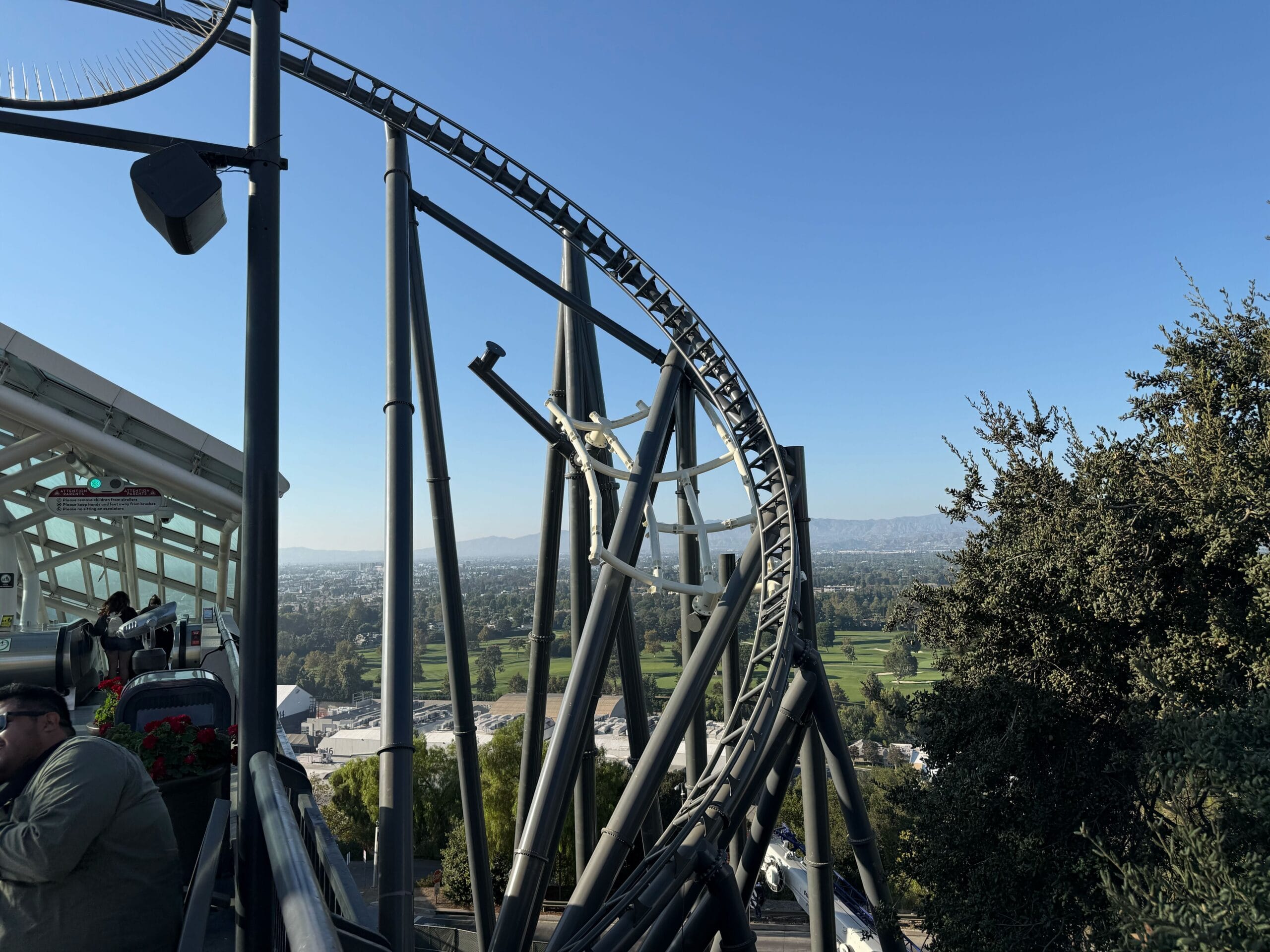 The Fast & Furious: Hollywood Drift roller coaster track curves under the escalator platform on the Upper Lot at Universal Studios Hollywood.
