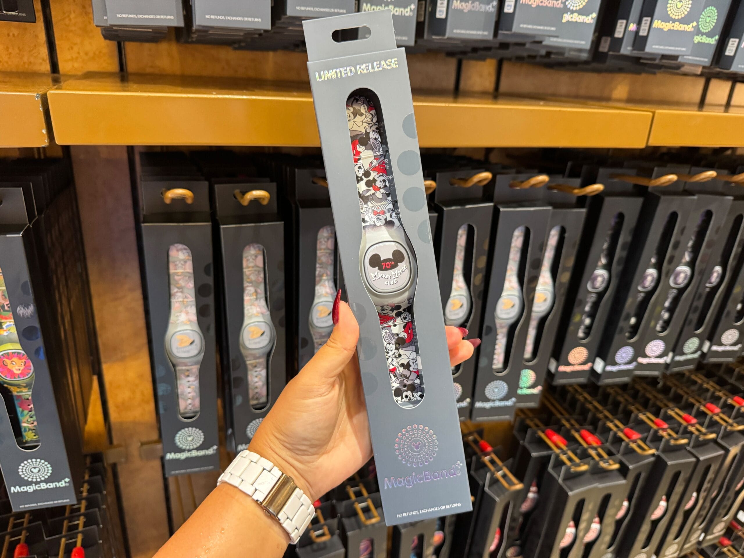 Hand holding a limited release Disney World MagicBand+ featuring a Mickey Mouse Club 70th Collection design on display.