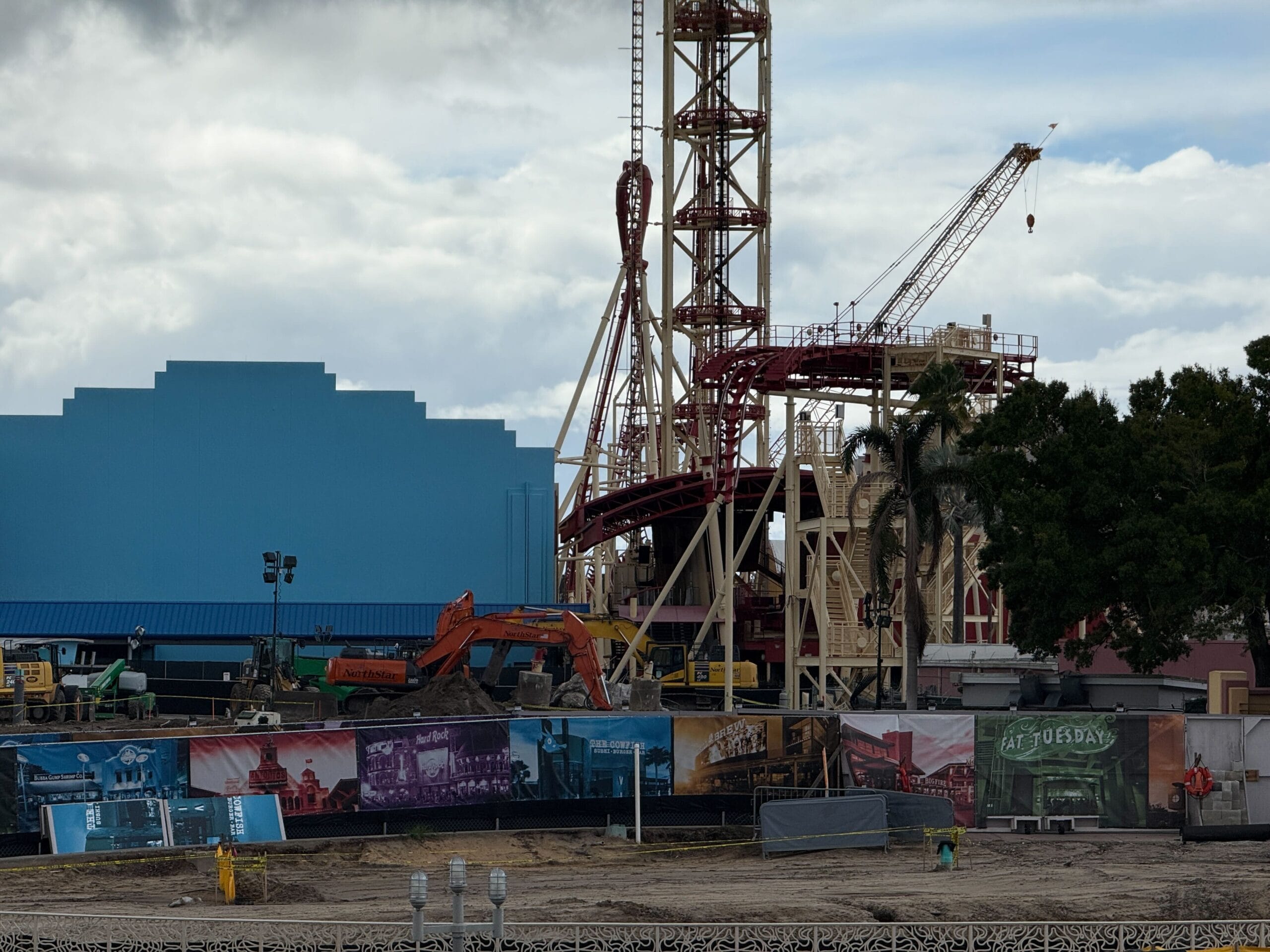 The Hollywood Rip Ride Rockit lift hill still towers above the coaster's demolition site with construction equipment, dirt mounds, a crane, and construction walls.