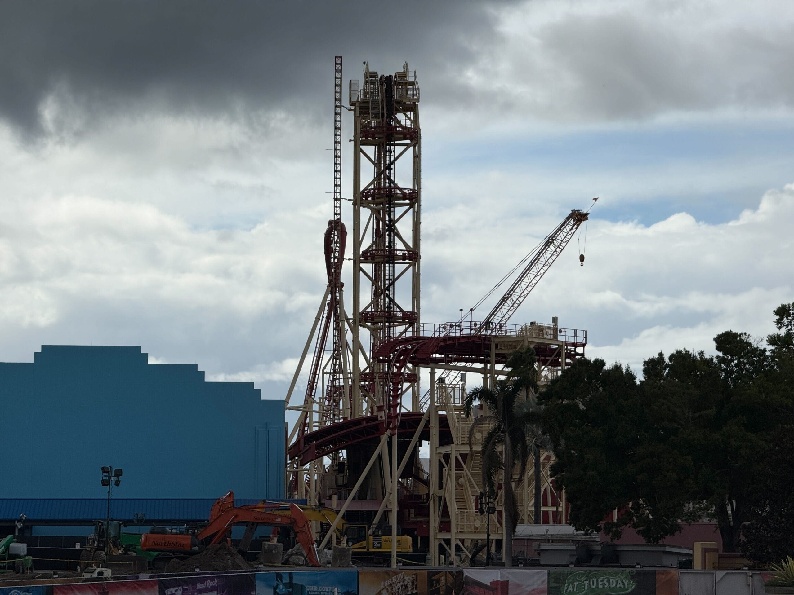 The Hollywood Rip Ride Rockit lift hill still towers above the coaster's demolition site with construction equipment, dirt mounds, a crane, and construction walls.