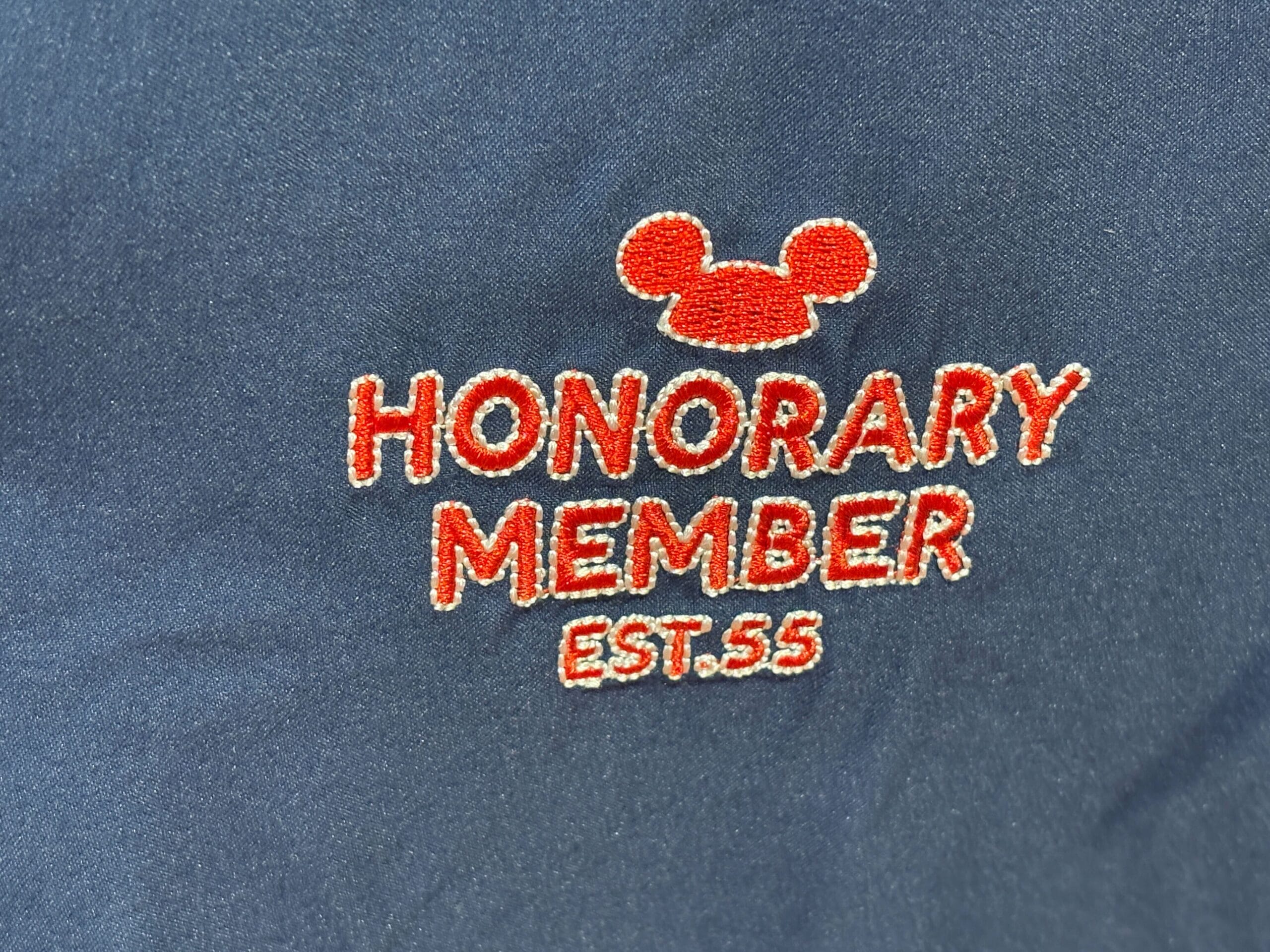 Red text "HONORARY MEMBER EST. 55" with Mickey Mouse Club ears, embroidered on dark fabric.