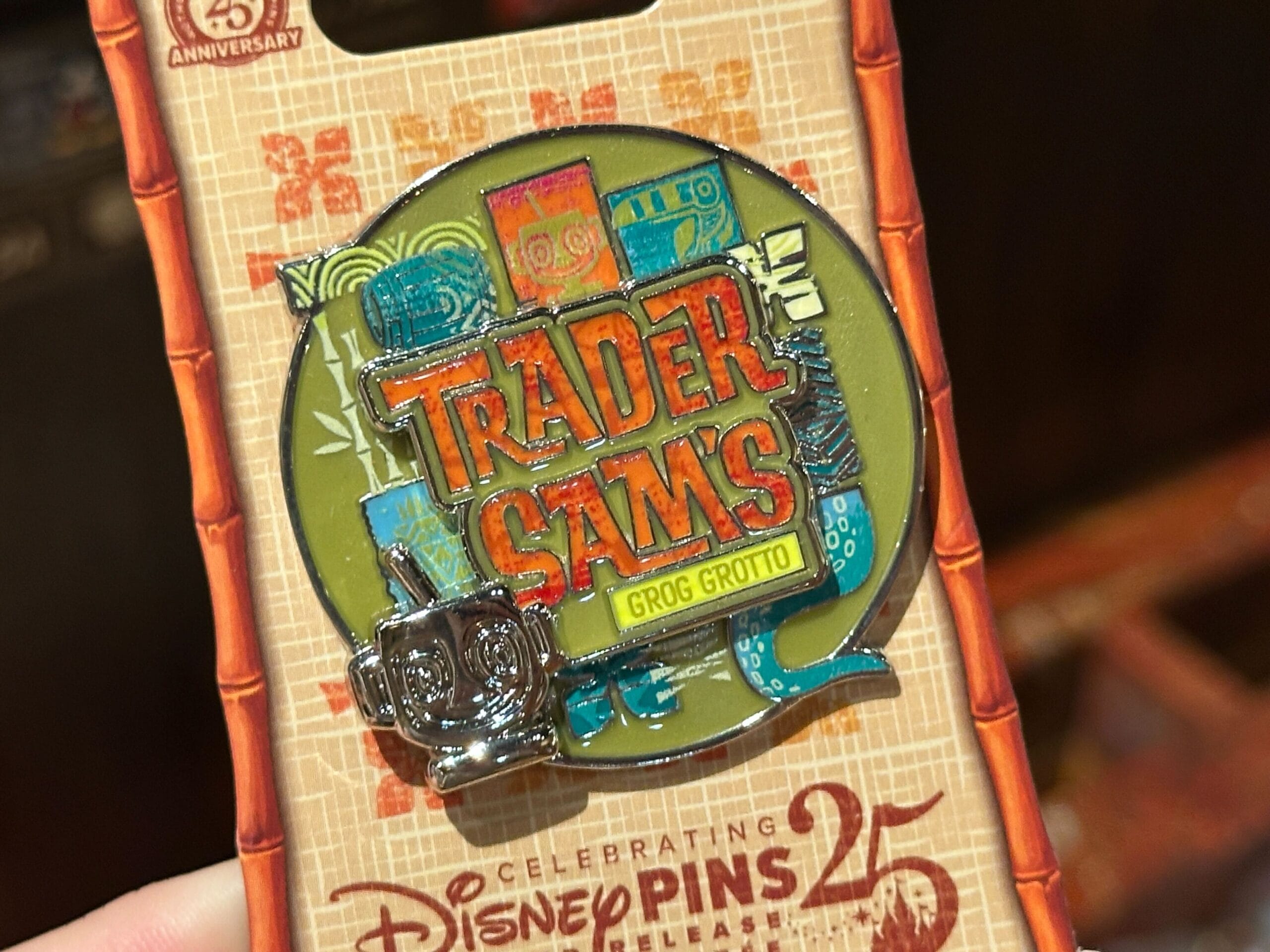 A colorful Trader Sam's Grog Grotto pin on Disney Pins 25th Anniversary packaging.
