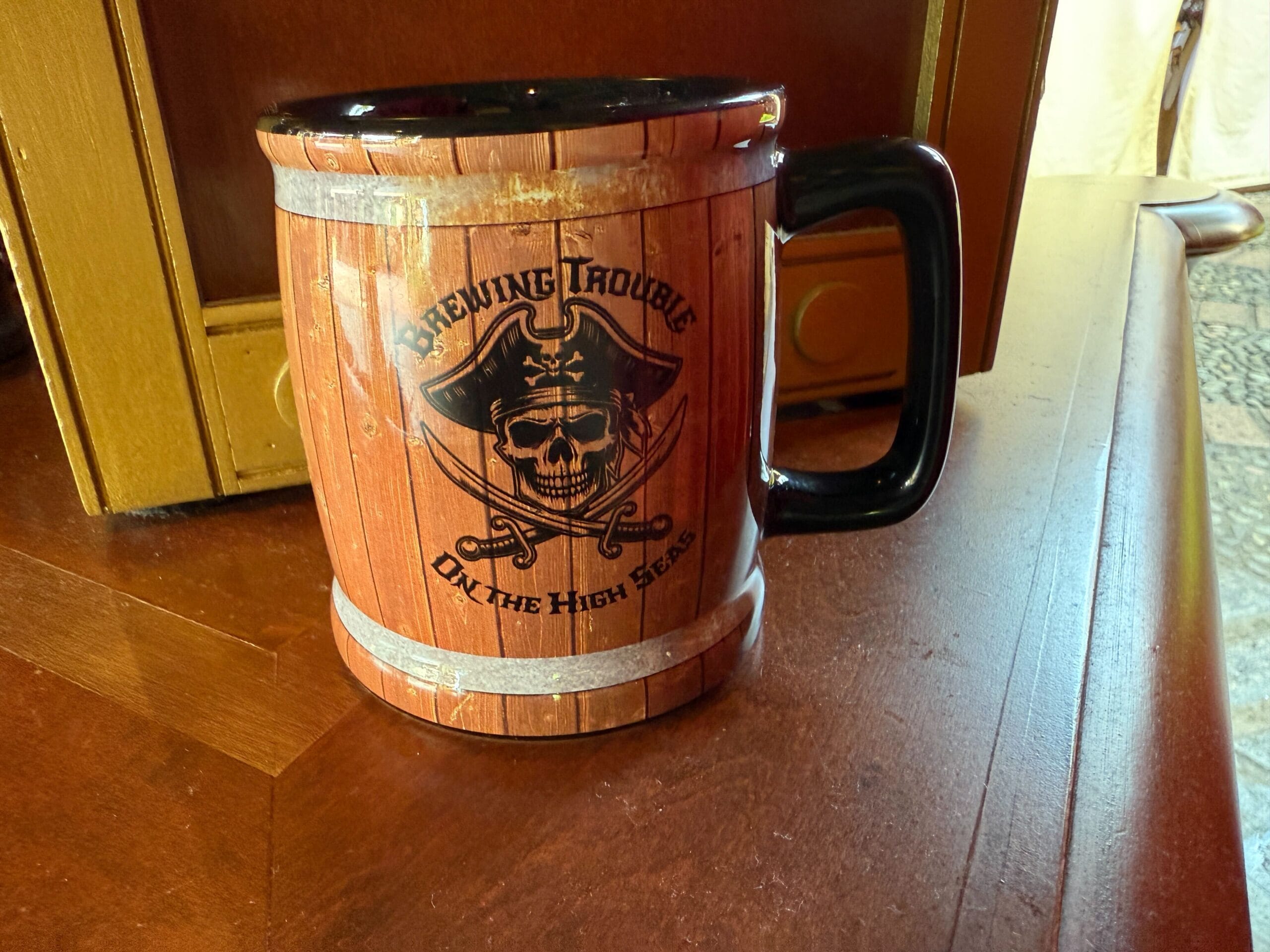 A brown barrel-inspired mug with a pirate skull and "Brewing Trouble on the High Seas."