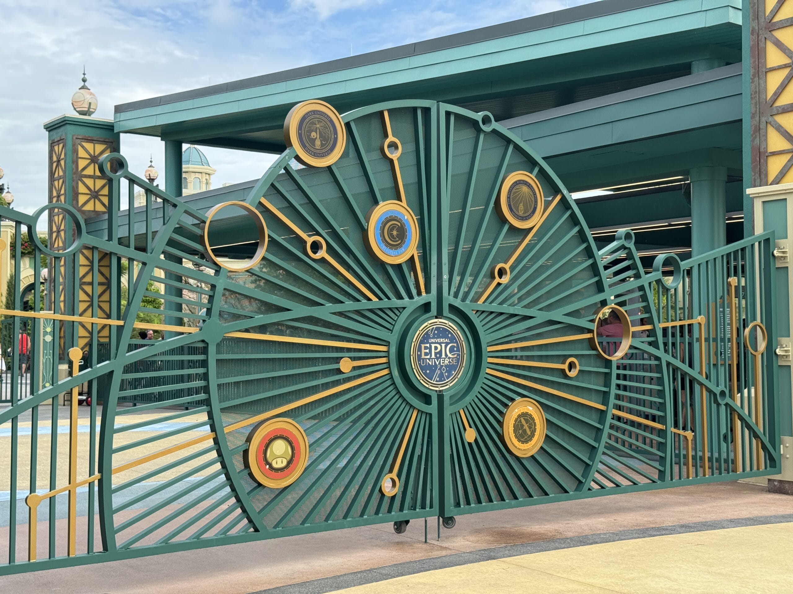 Green and gold gate with "EPIC Universe" logo, geometric patterns—perfect for a rainy day adventure.