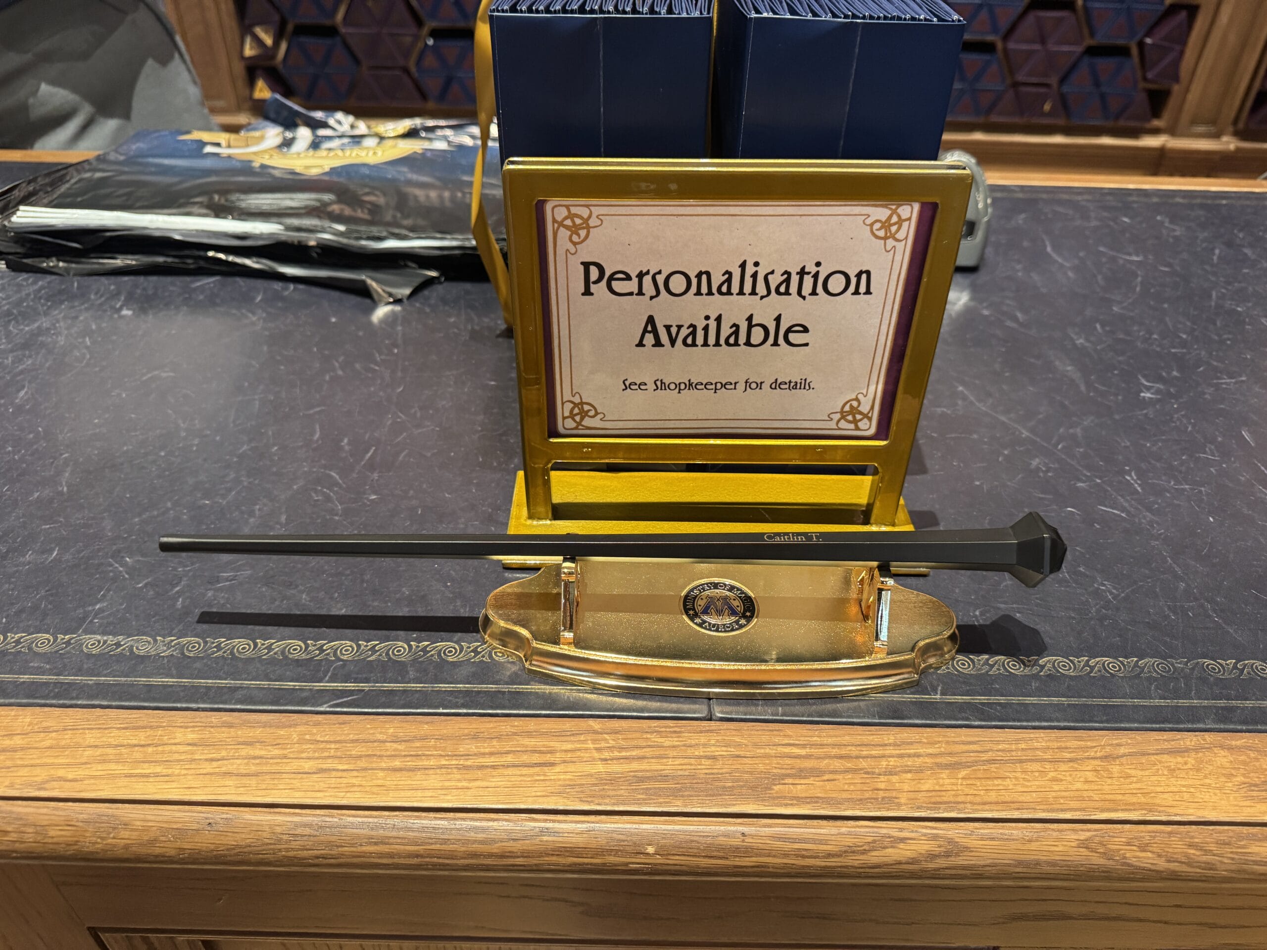 Black wand displayed on a counter with a sign reading "Personalize Your Wand. See Shopkeeper for details.