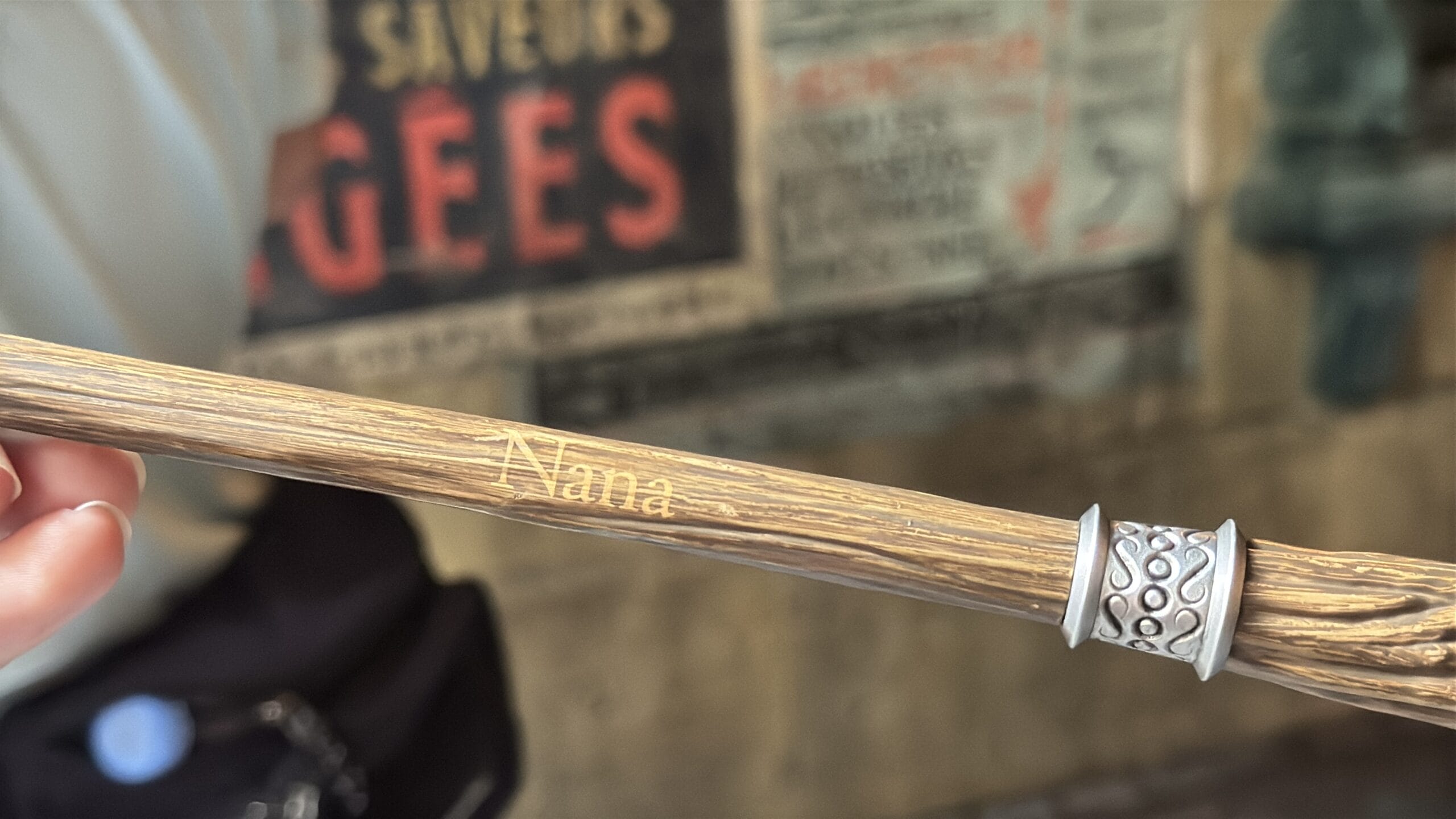 A hand holds a wooden wand engraved with "Nana"—personalize your wand for an Epic Universe adventure.