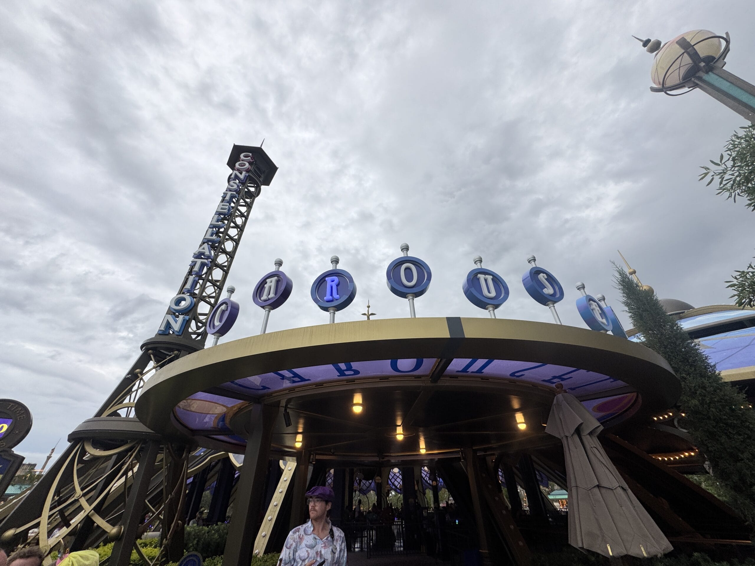 Entrance to the "CIRCUS" attraction at Epic Universe, with cloudy skies overhead and people walking below.