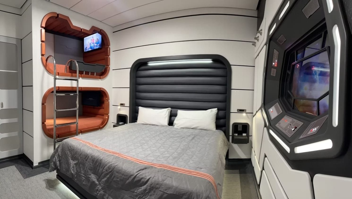 A futuristic hotel room with a large bed, bunk beds, and Star Wars–themed Galactic Starcruiser Replica decor.