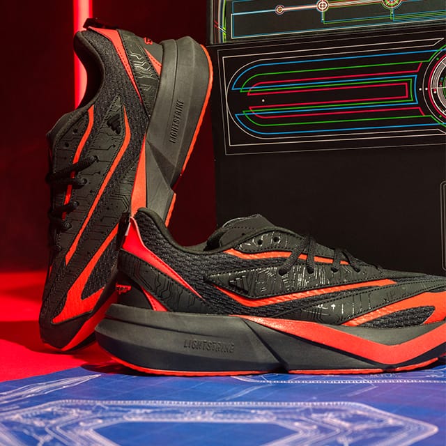 A pair of black and red Adidas TRON: Ares Lightblaze sneakers with circuitboard details.
