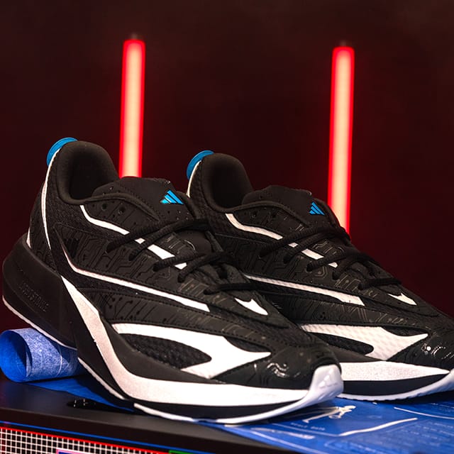 A pair of black and white Adidas TRON: Ares Lightblaze sneakers with circuitboard details and blue accents.
