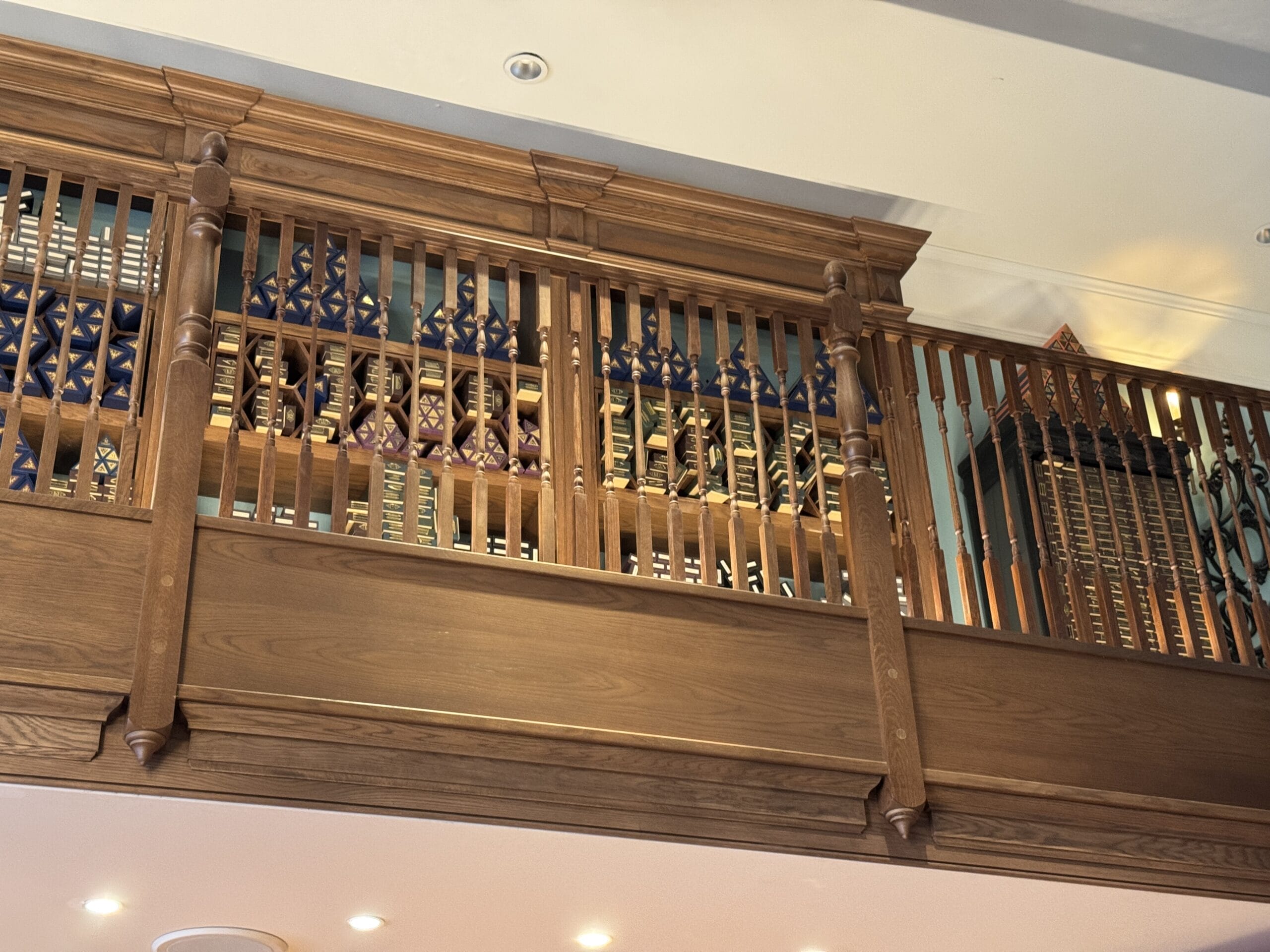 Wooden balcony railing with Cosme Acajor wine bottles and decorative items displayed behind the slats.