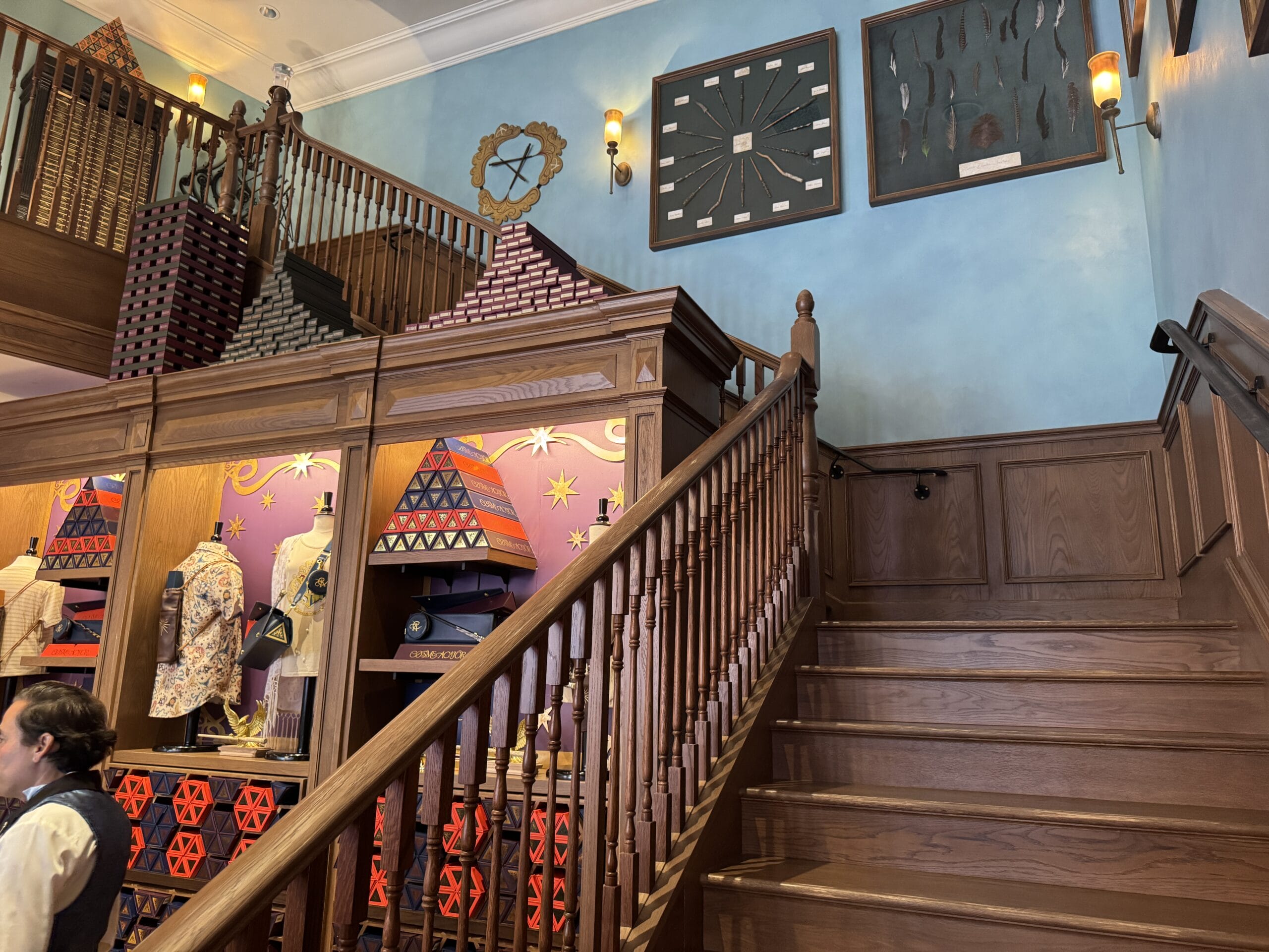 Wooden staircase beside Cosme Acajor’s gift shop display with colorful clothing, wall art, and geometric decorations.