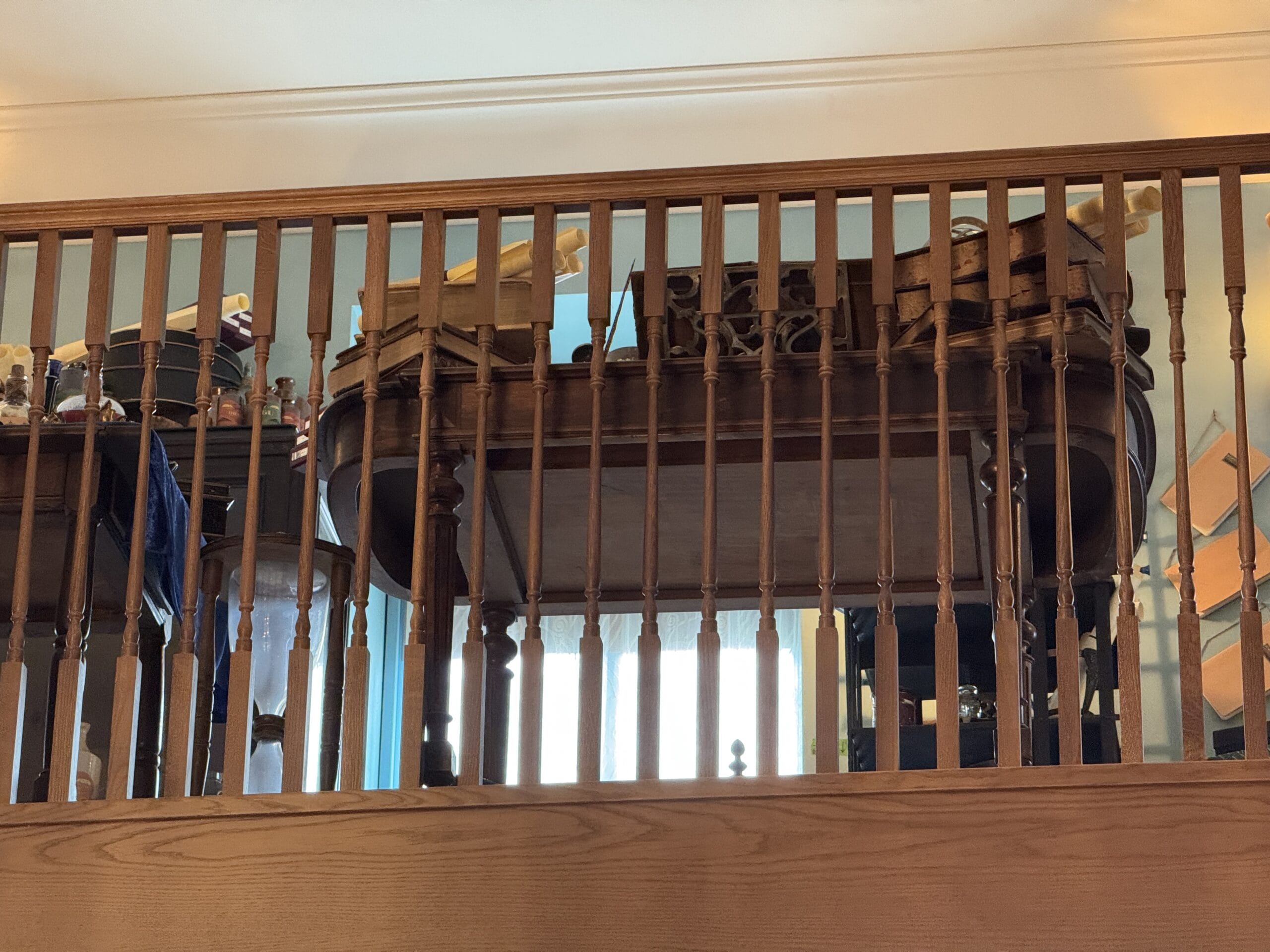 A wooden piano behind vertical Cosme Acajor railings, viewed from below with sunlight filtering in the background.