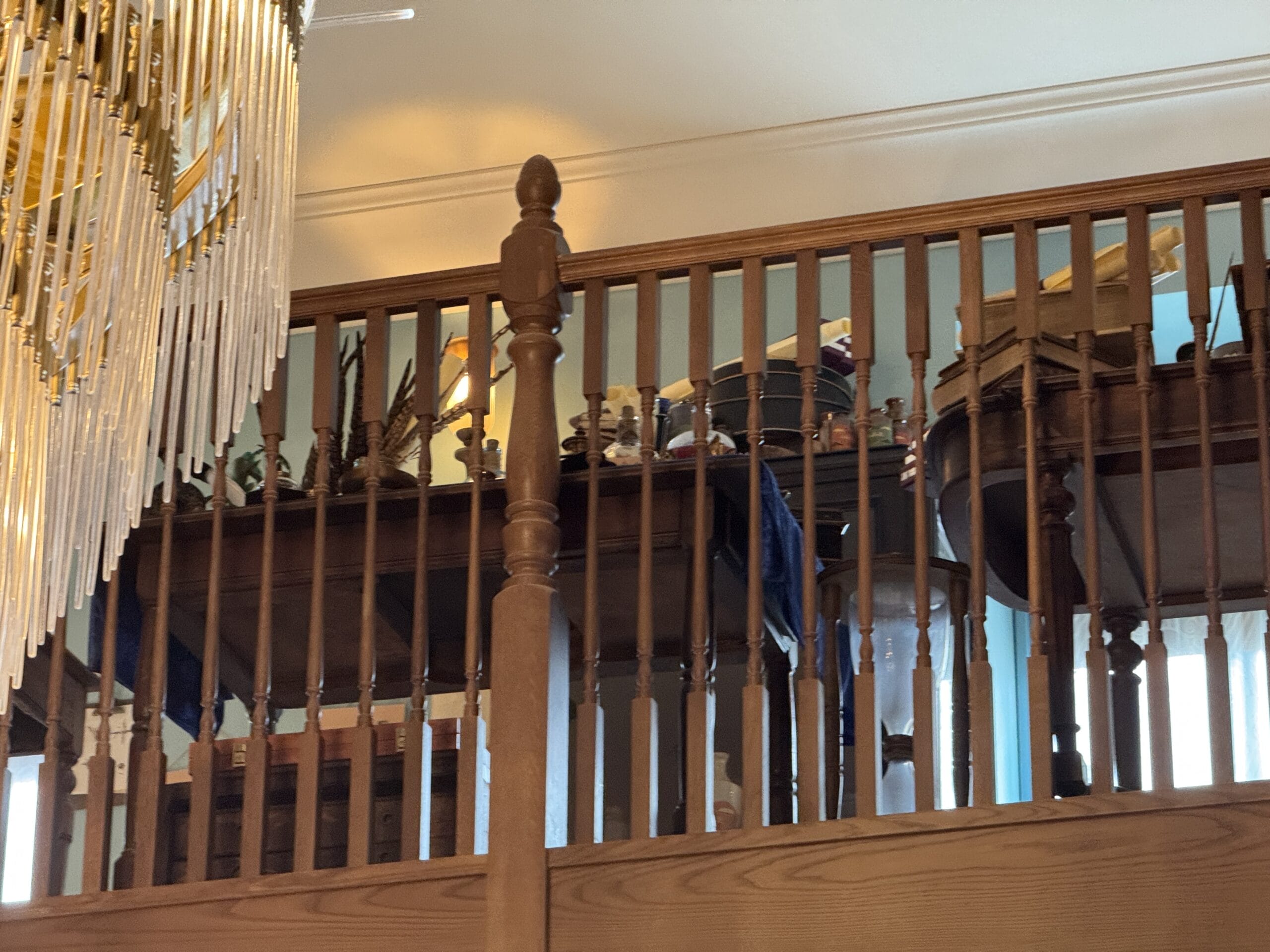 A wooden railing overlooks a balcony above, featuring Cosme Acajor instruments and decorative items.