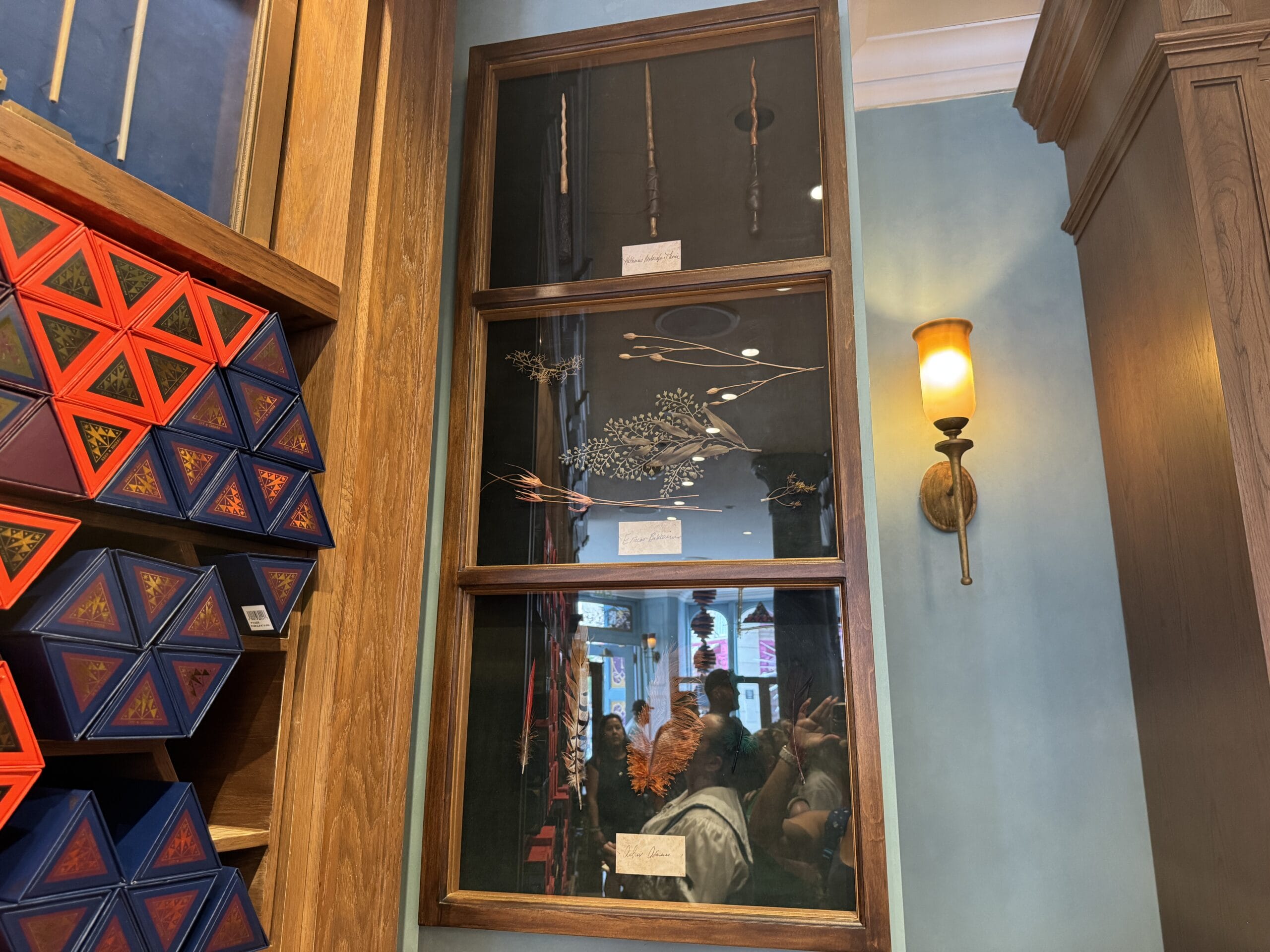 A Cosme Acajor wall display holds Baguettes Magique, beside geometric boxes and a glowing sconce in the shop.