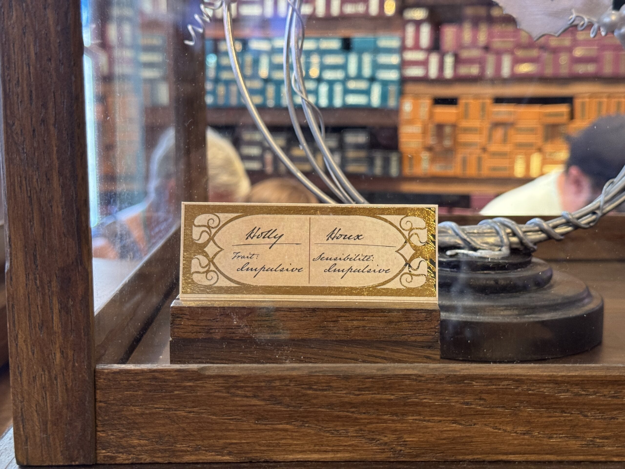 A display label for Cosme Acajor Baguettes Magique: "Holly, Phoenix, Trust: Unyielding, Sensibility: Unyielding" in wood case.