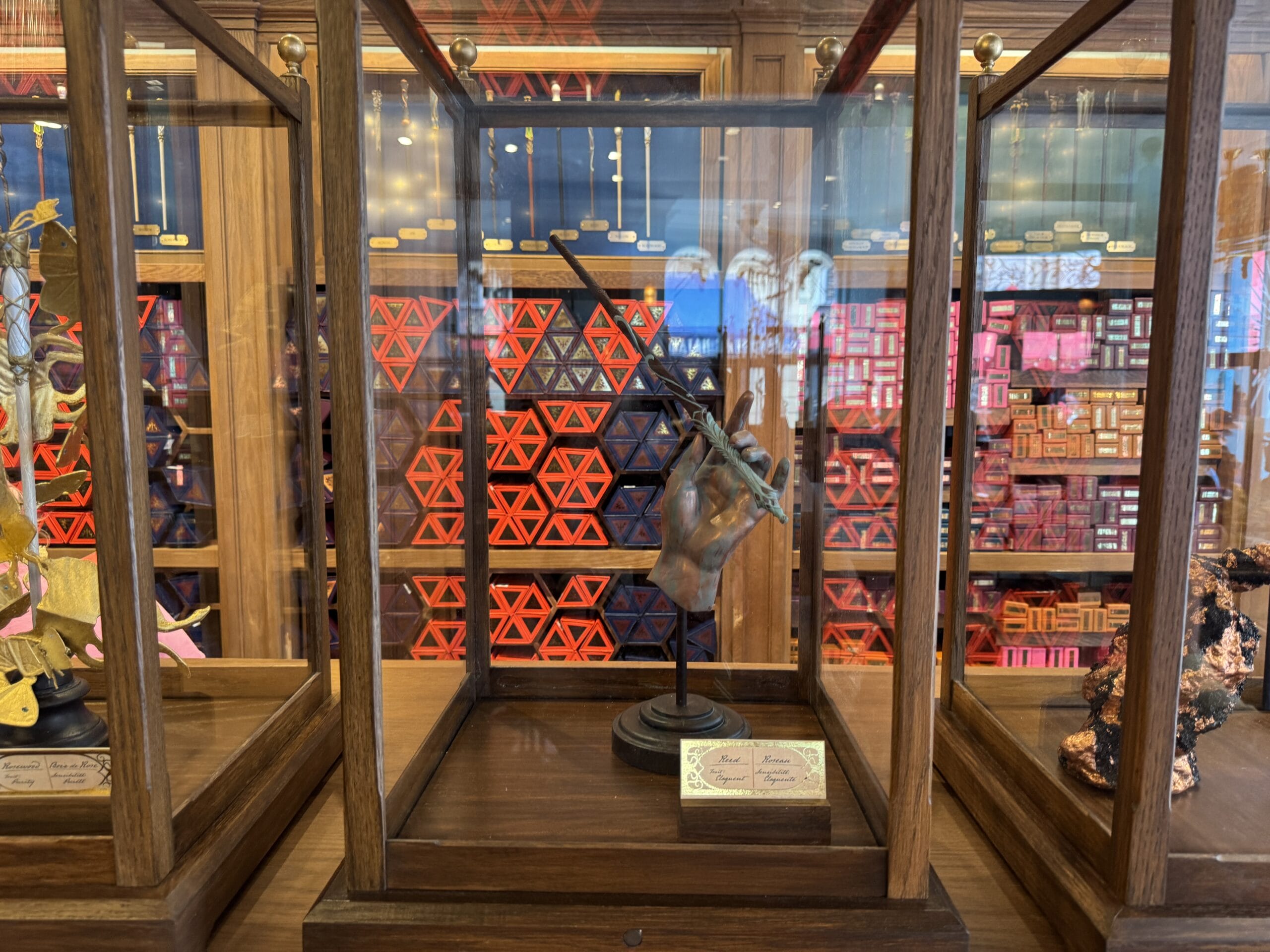 A display case showcases a Cosme Acajor Baguettes Magique hand sculpture, with red hexagonal box patterns behind.