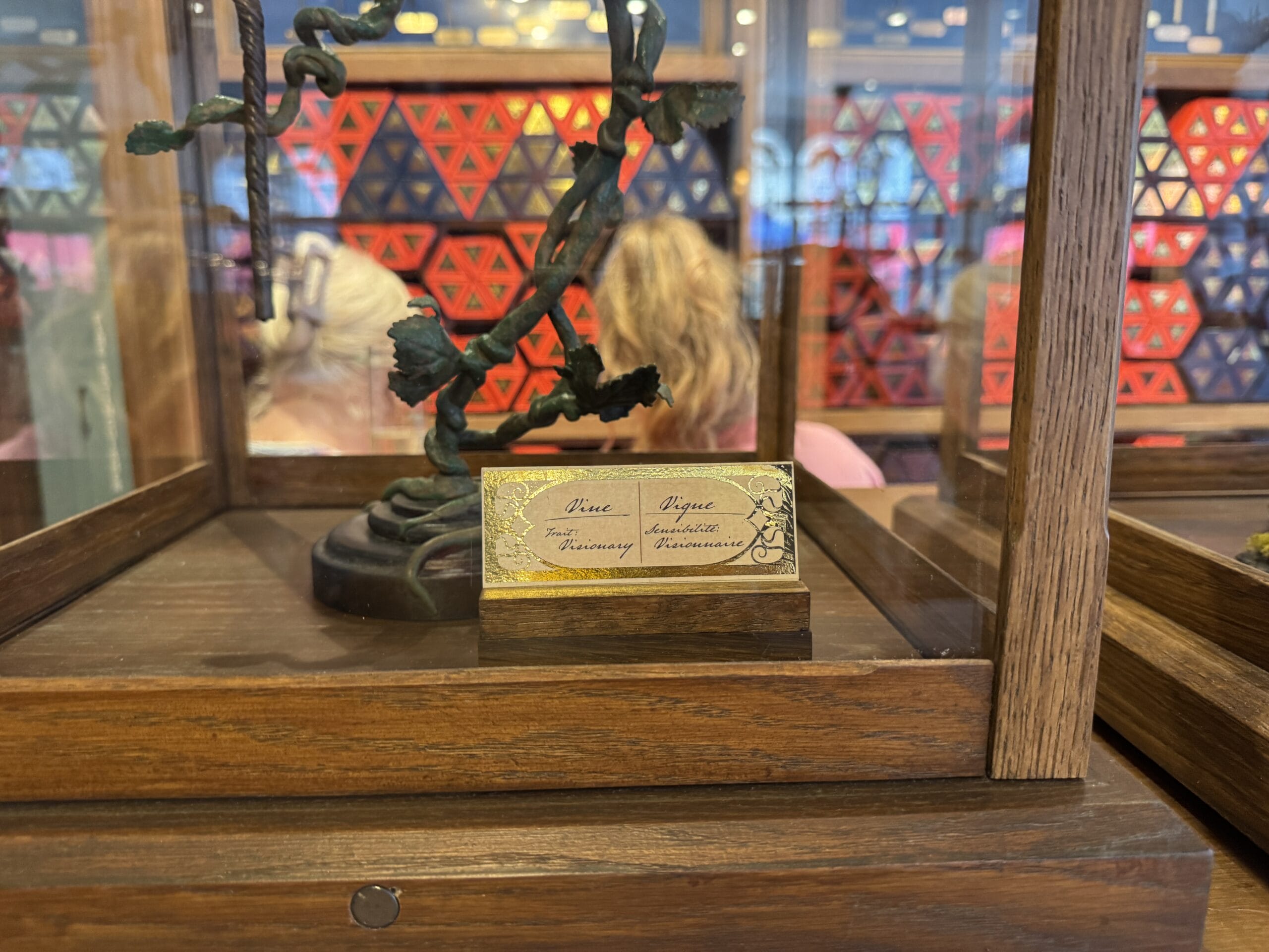 A display case with a gold plaque labeled "Three Rogue Enchanted Fireways" and Cosme Acajor Baguettes Magique sculpture.