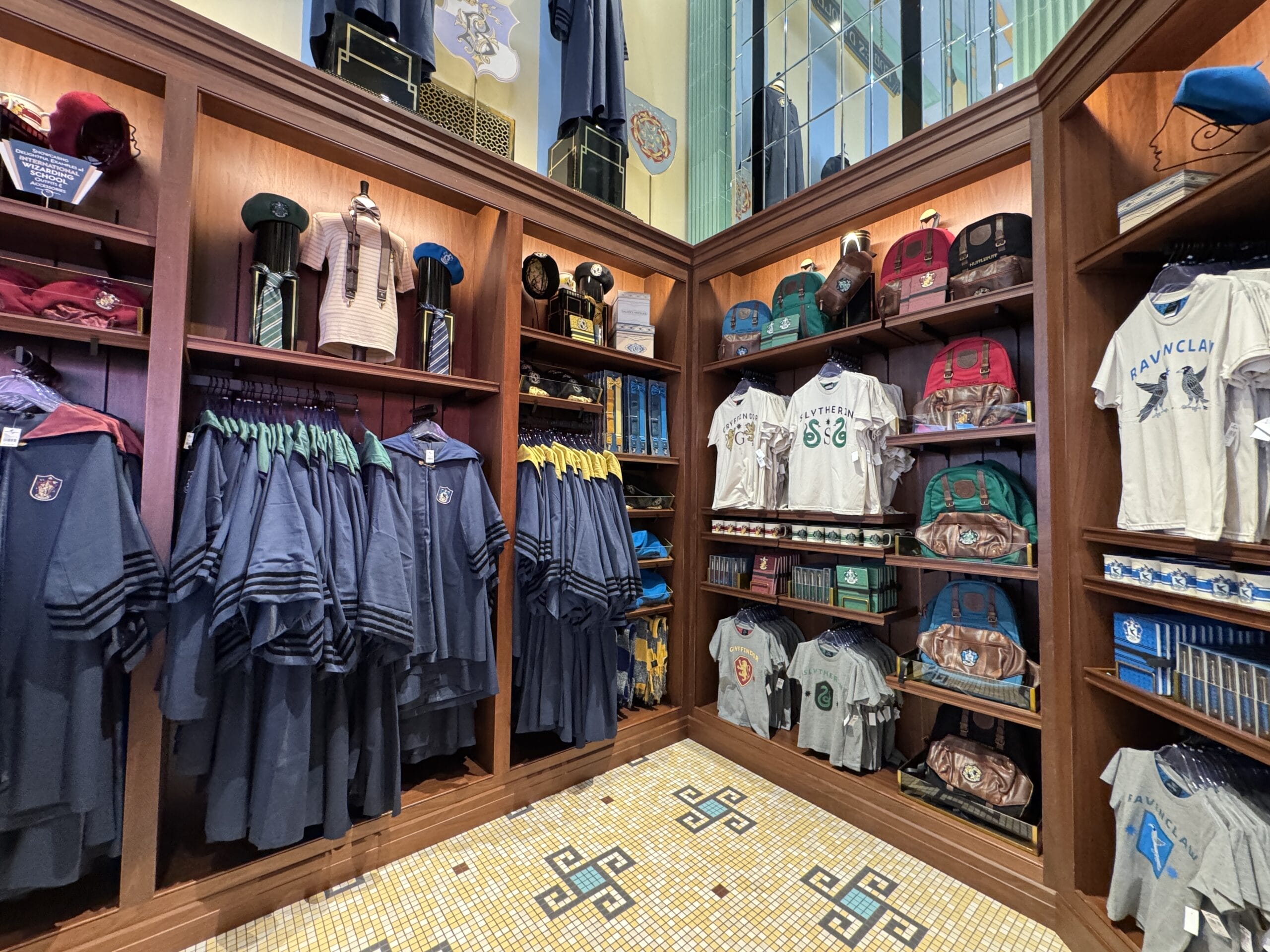 Les Galeries Mirifiques offers Harry Potter-themed robes, ties, shirts, and backpacks displayed on magical shelves.