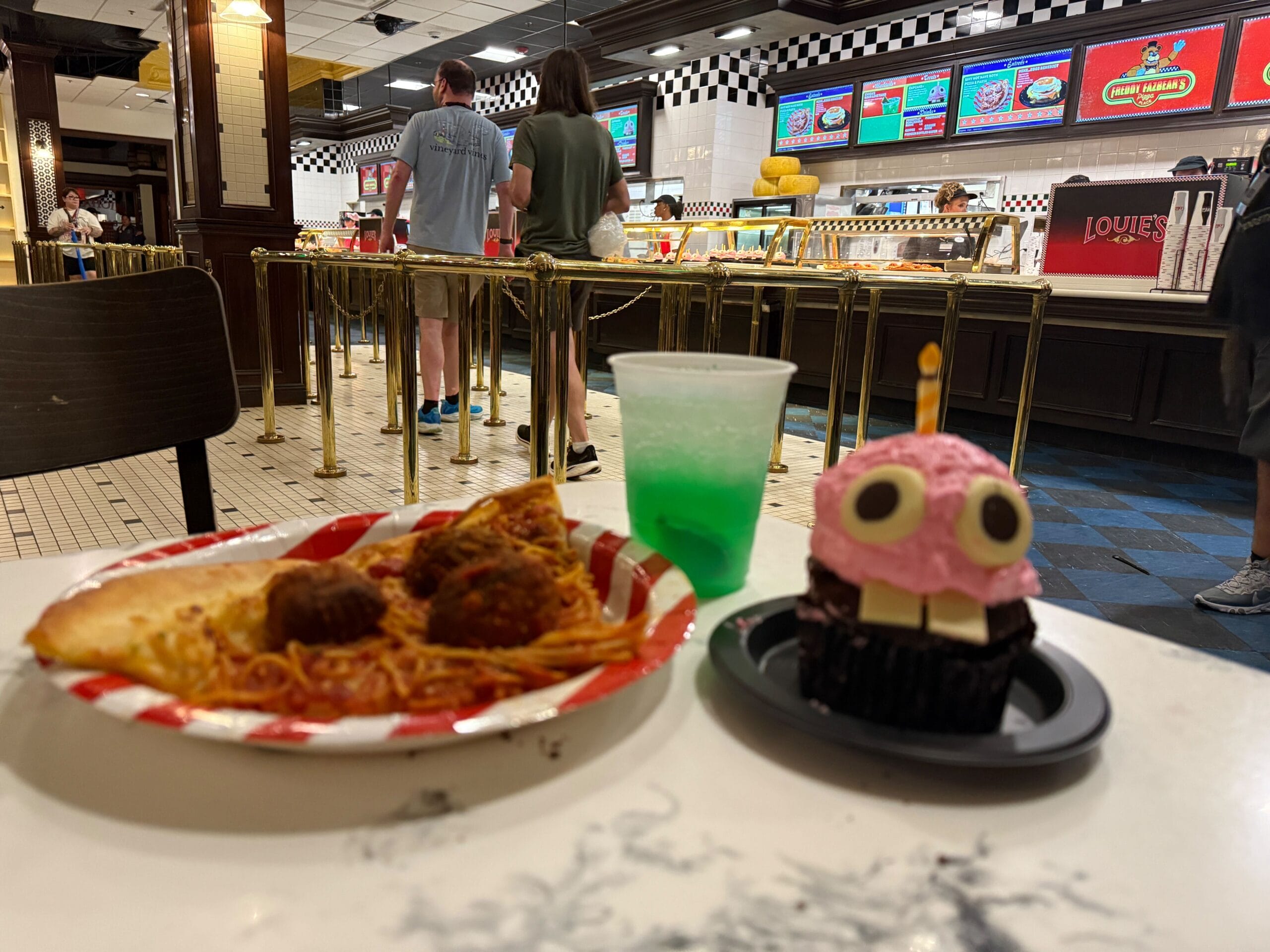 A plate of spaghetti, meatballs, pizza, and a pink monster cupcake—perfect for a Halloween Horror Nights review.