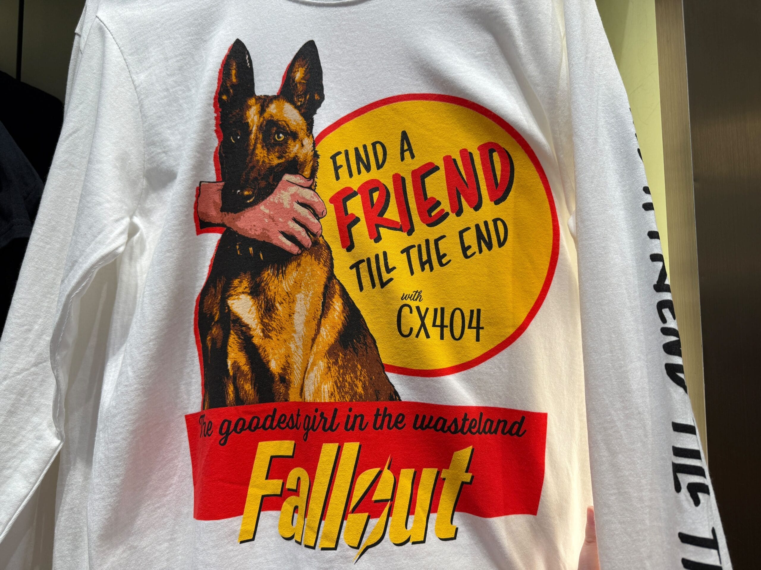 A shirt features a dog, an arm, and text: "Find a friend till the end with CX404. The goodest girl in the wasteland. Fallout.