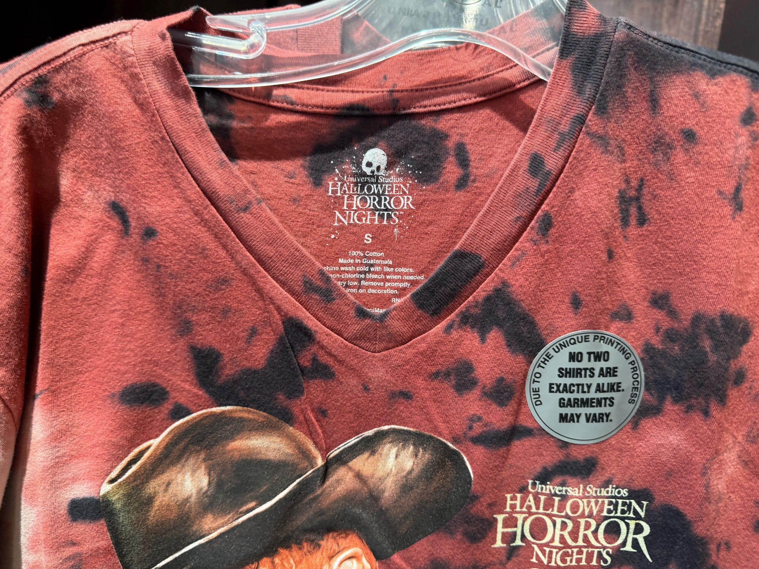 A red Halloween Horror Nights shirt with black stains, a Freddy Krueger print, and a “No two shirts are exactly alike” sticker.