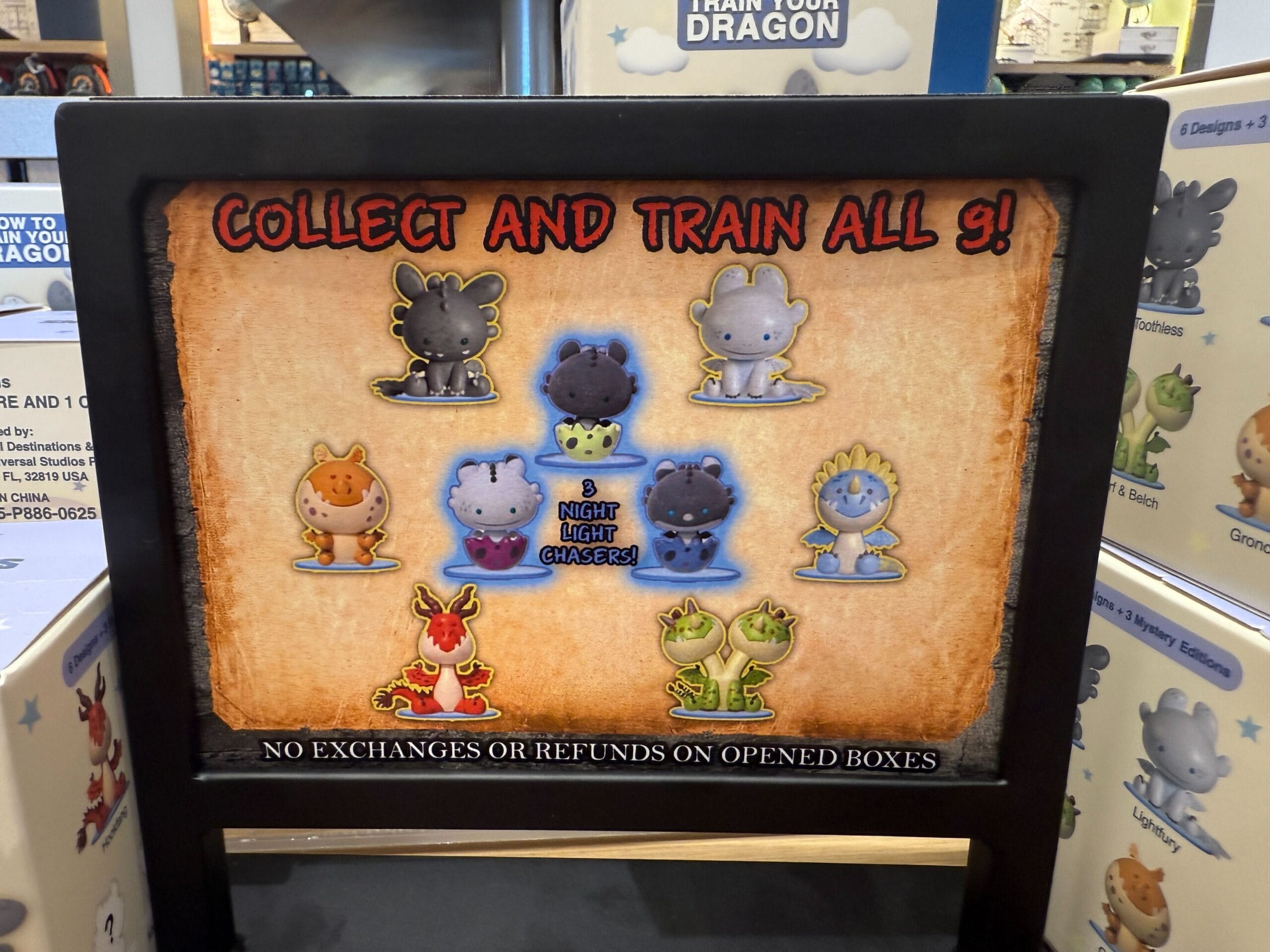 Display showing nine cartoon dragon figures with text: "Collect and train all 9! No exchanges or refunds on opened boxes.
