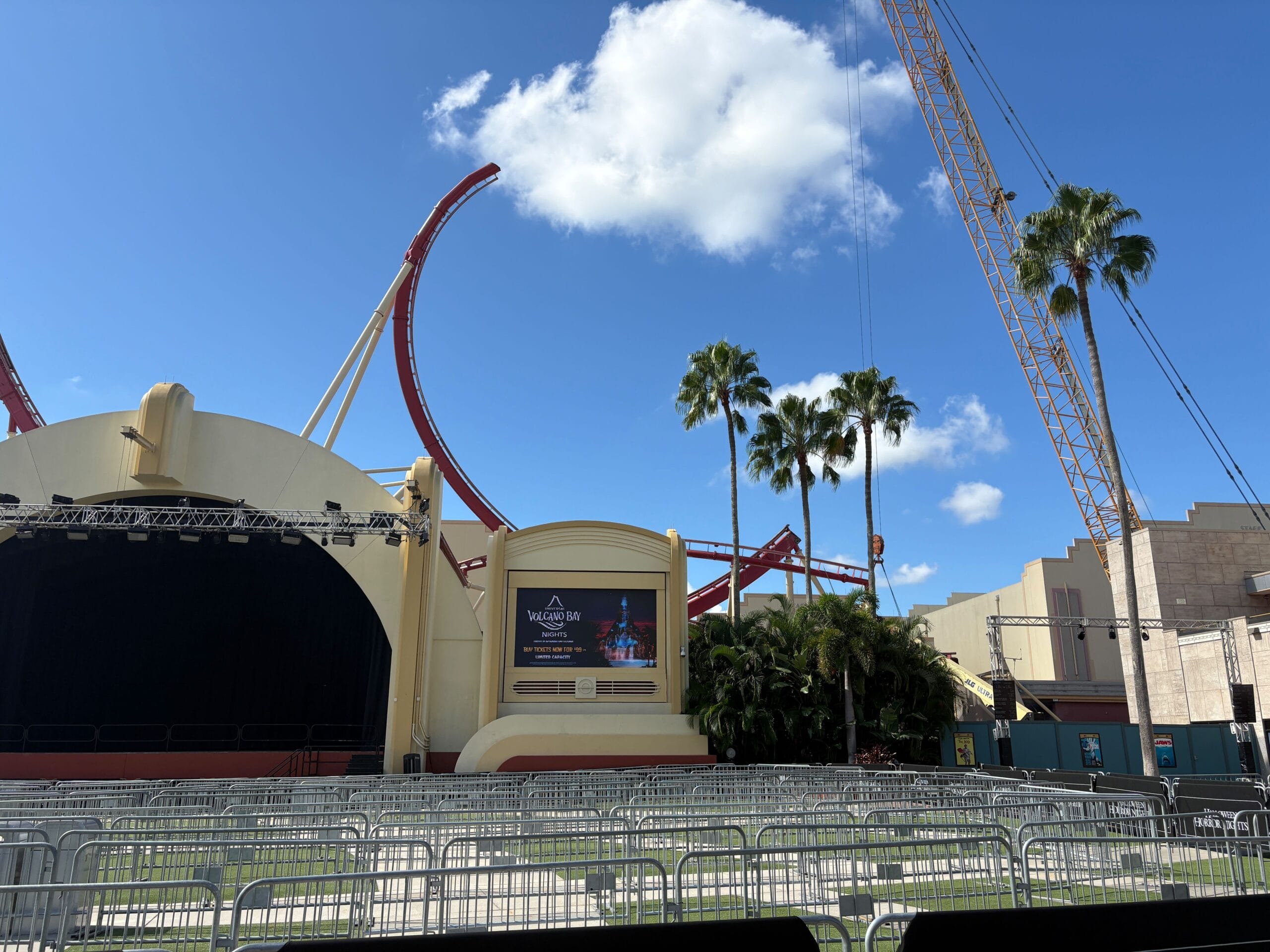 Outdoor stage with empty seating, Rip Ride Rockit track removal visible near palm trees and crane at Universal Studios.