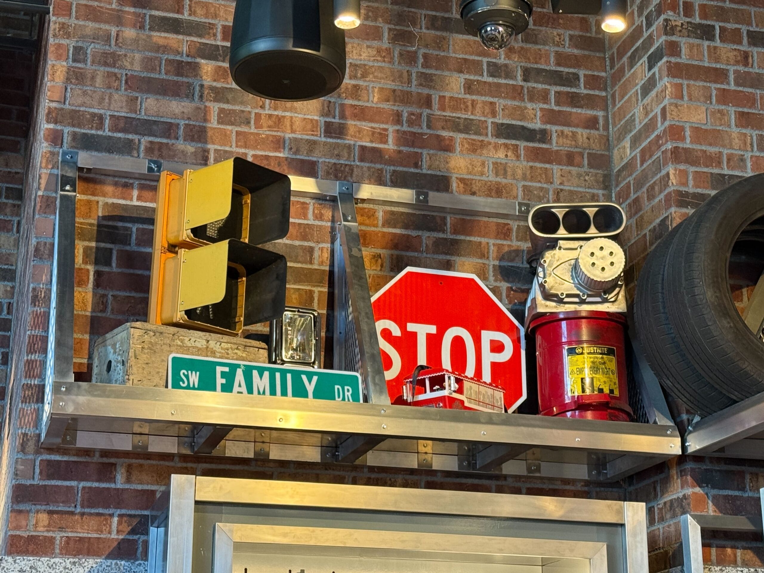 Traffic light, stop sign, SW Family Dr street sign, fire hydrant, and tire at Fast & Furious Store against a brick wall.