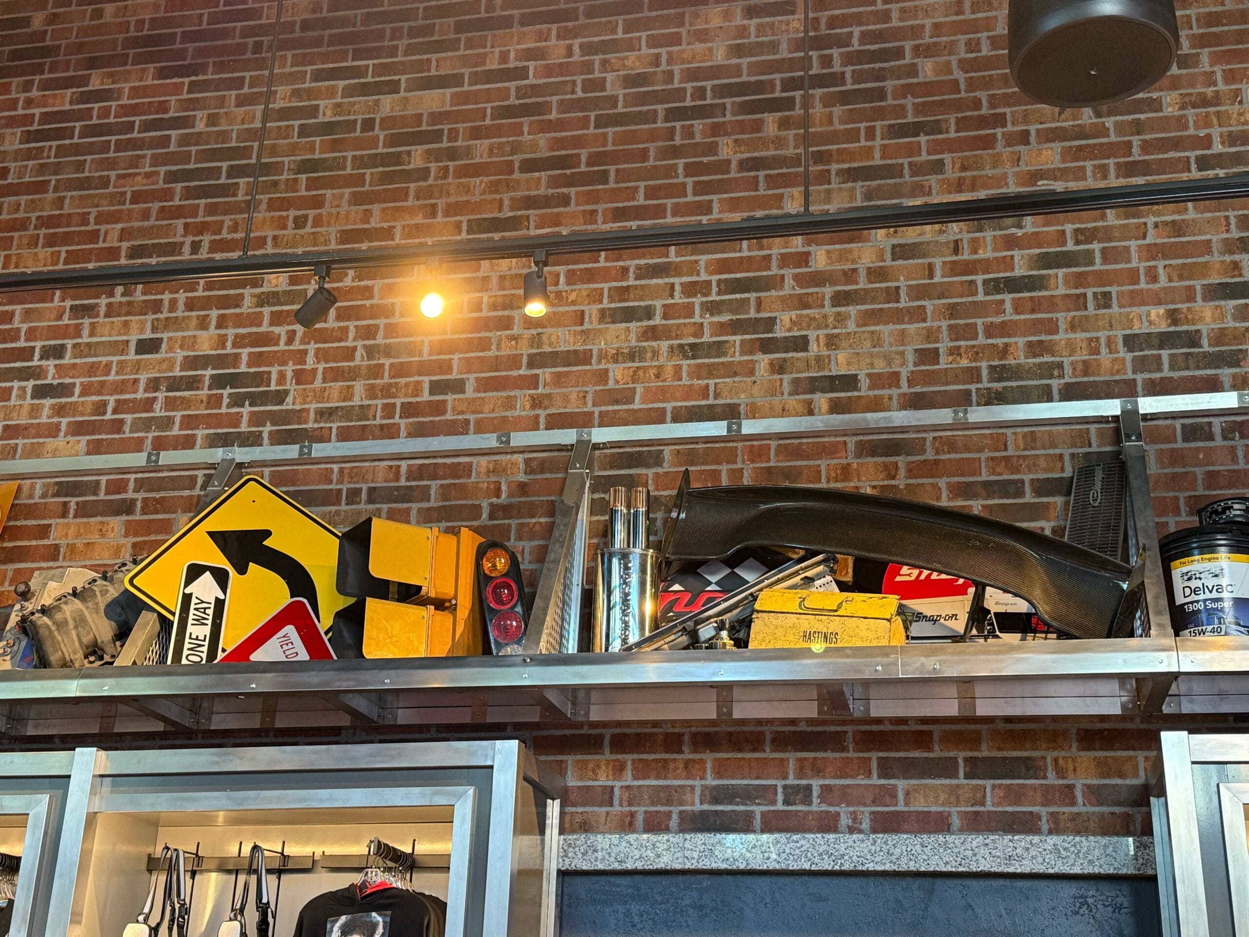 Metal shelf displaying Fast & Furious merchandise, road signs, and tools against a brick wall under track lighting.