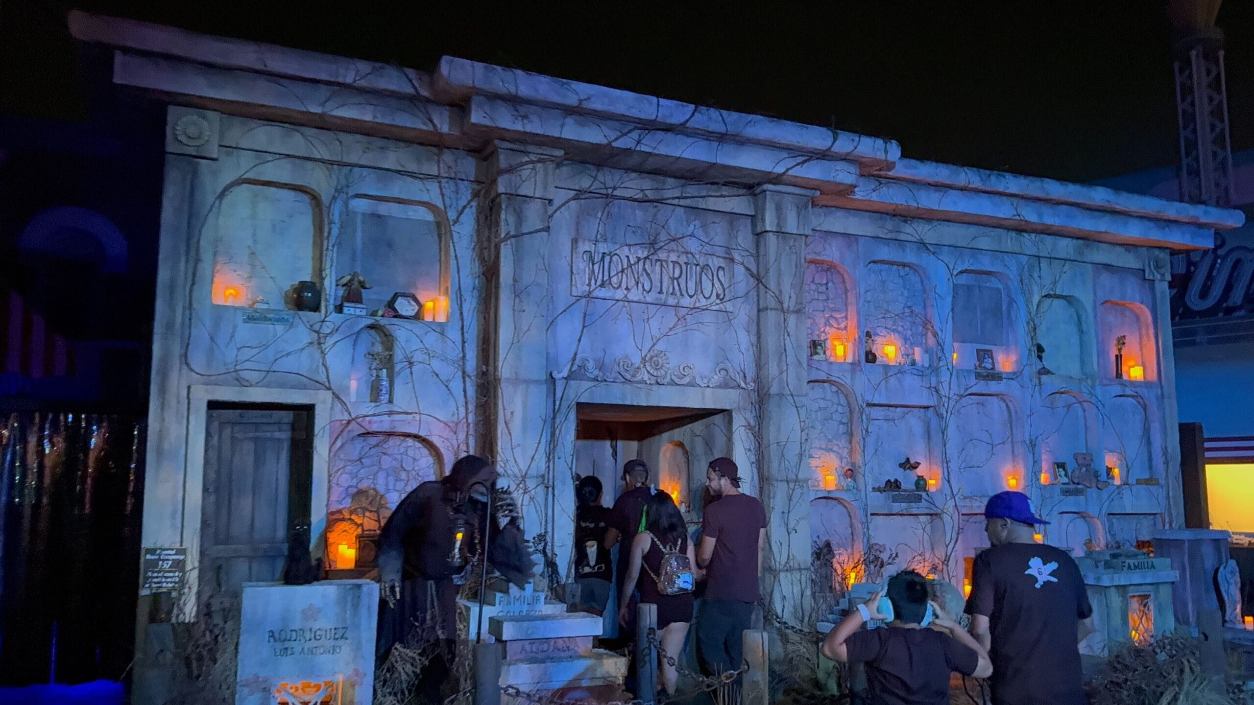People enter a haunted mausoleum with glowing orange lights at USH during Monstros 3: HHN 2025.
