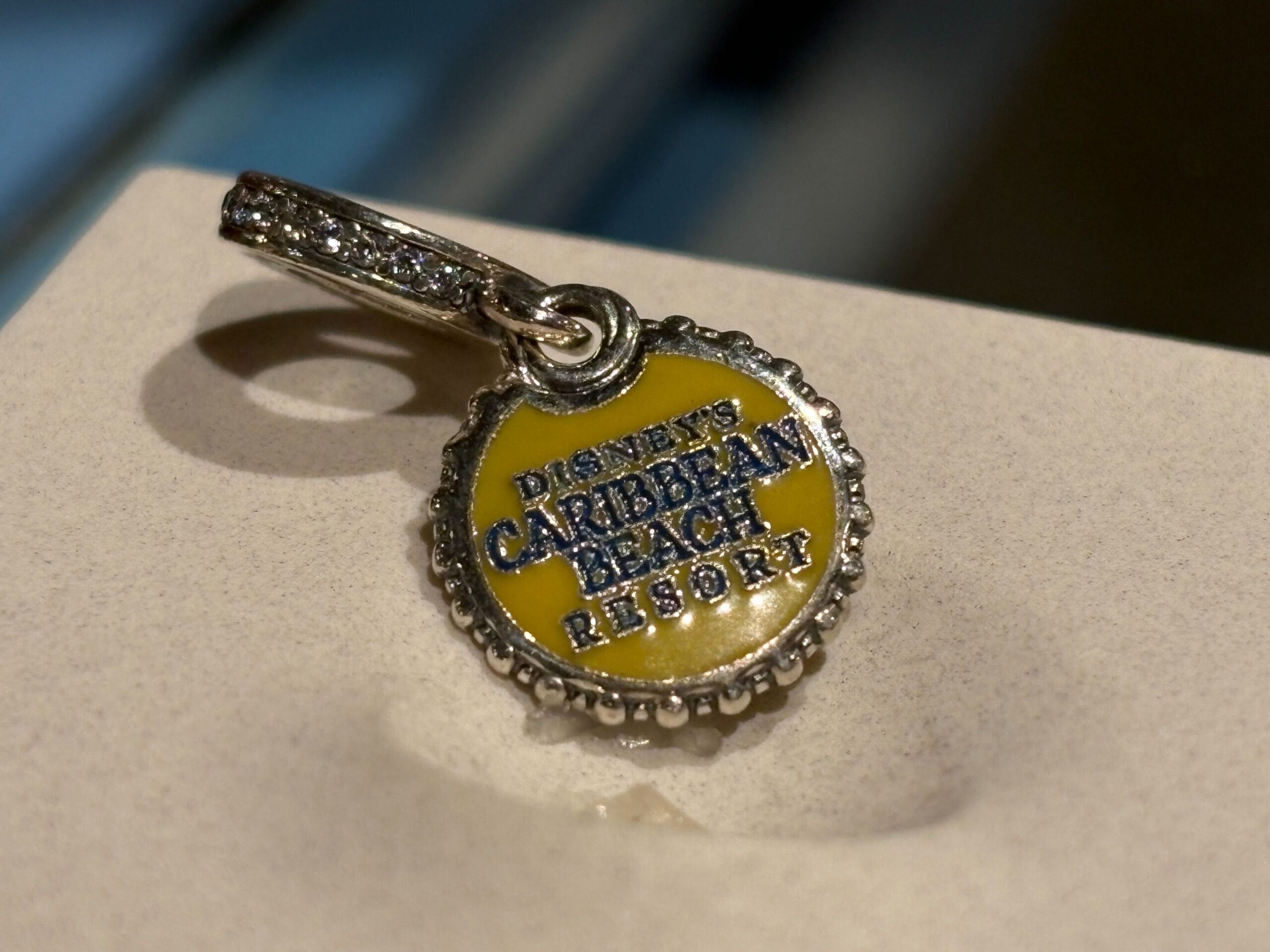 A round yellow charm reads "Disney's Caribbean Beach Resort" with a silver, gemmed loop for attaching.