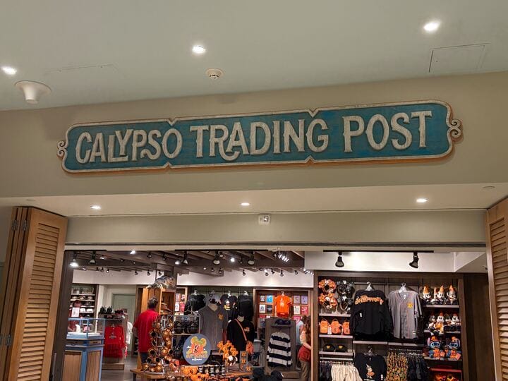 Sign reading "Calypso Trading Post" above a store selling various merchandise, including clothing and plush toys.