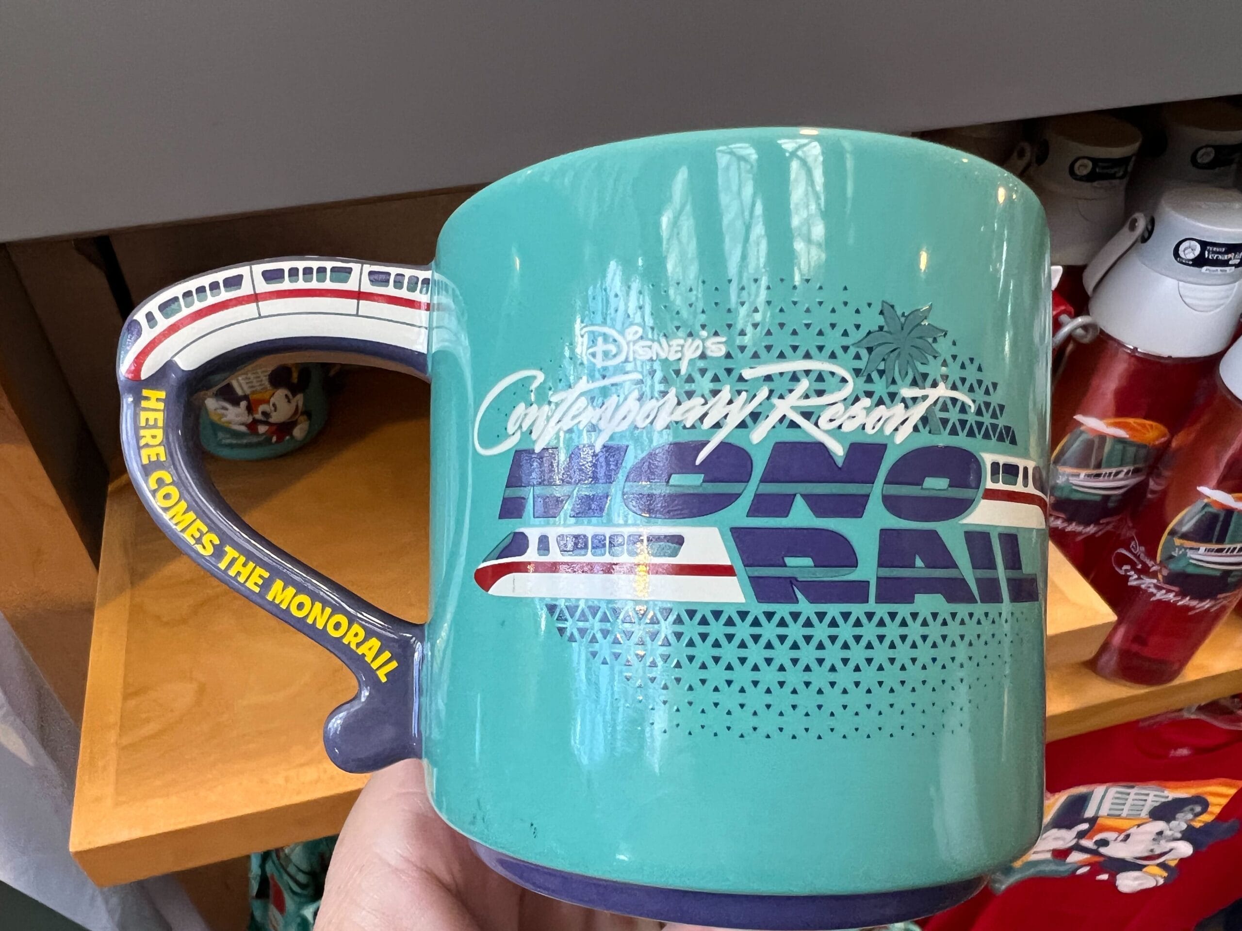 Turquoise mug from the Monorail Collection features Disney's Contemporary Resort and a monorail-shaped handle.