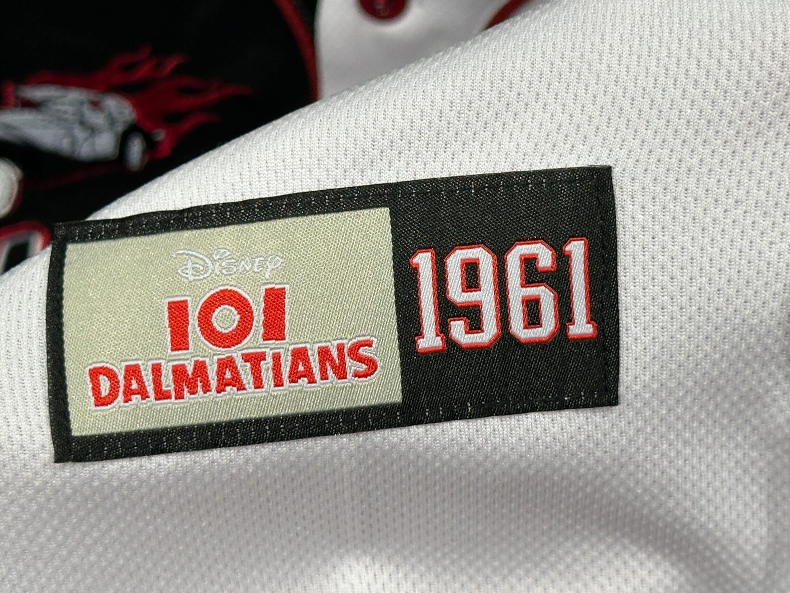 Close-up of a patch reading "Disney 101 Dalmatians 1961" on a white Baseball Jersey fabric.