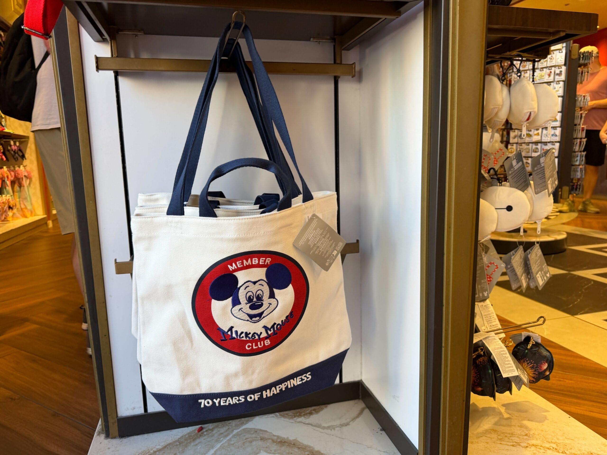 White and navy Disney Parks tote bag from the 70th Collection, with Mickey Mouse Club logo and "70 Years of Happiness" text.