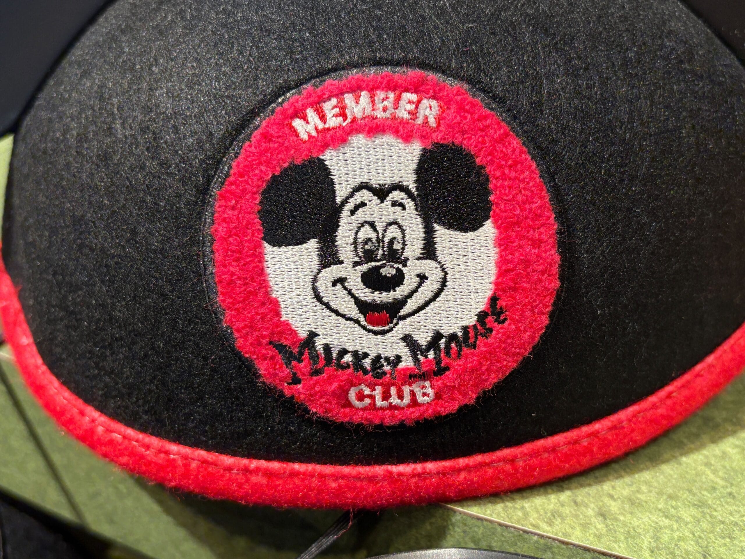Close-up of a black Mickey Mouse Club hat, part of the 70th Collection, with a patch showing Mickey’s face and "MEMBER.