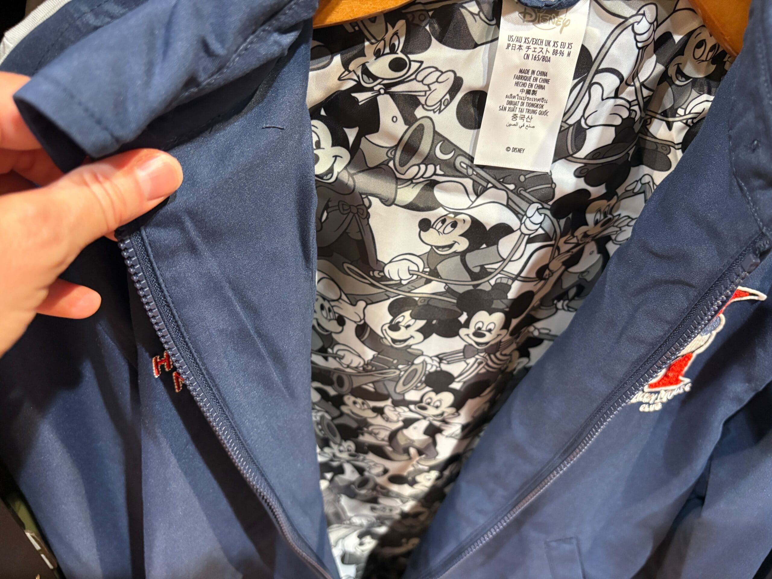 A blue jacket is unzipped to reveal a lining of black-and-white Mickey Mouse Club illustrations.