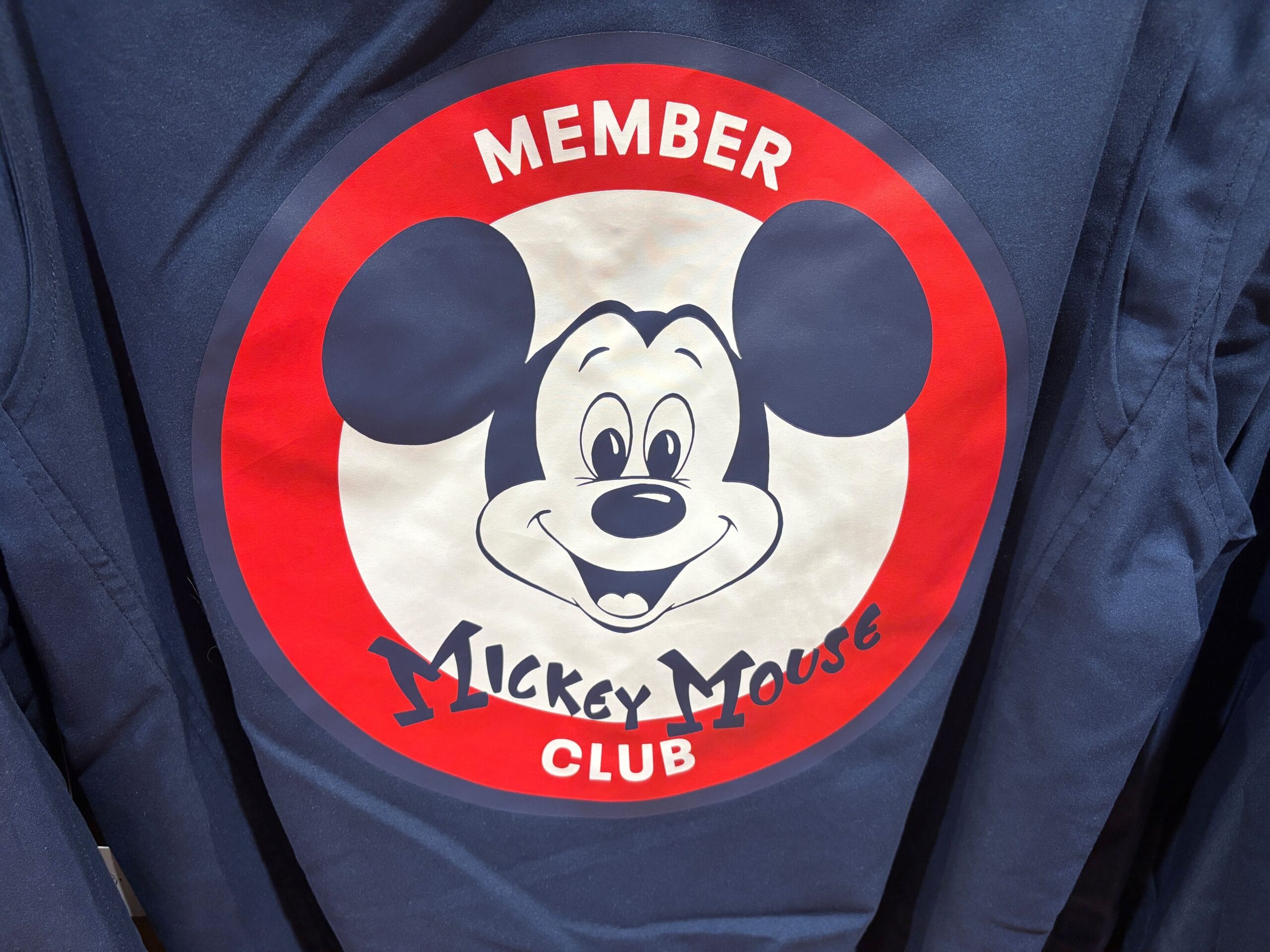 A Disney World Mickey Mouse Club logo with "Member" above and "Mickey Mouse Club" below a smiling Mickey face.