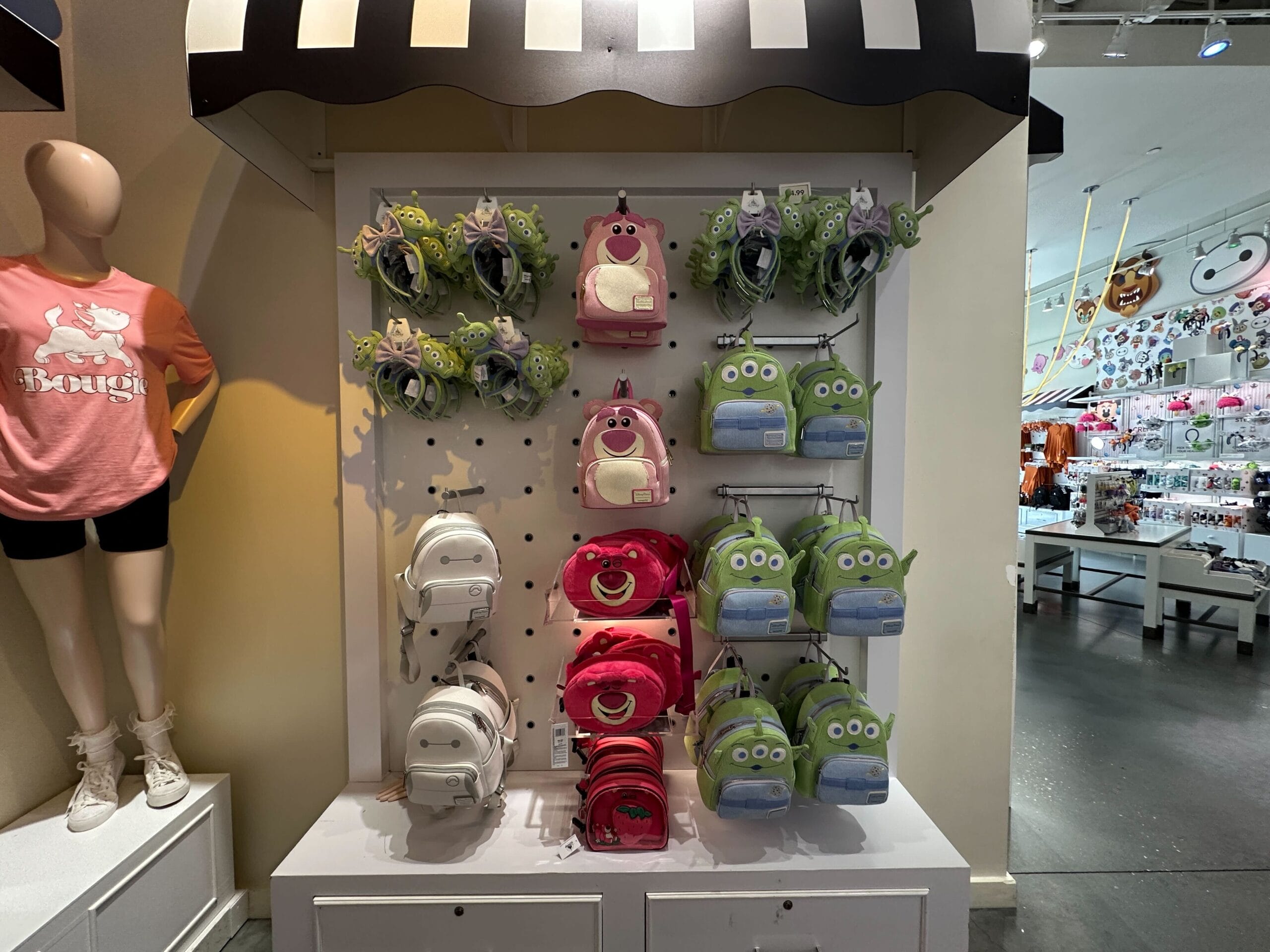 Display of Alien Loungefly plush backpacks shaped like Toy Story characters on shelves in a brightly lit retail store.